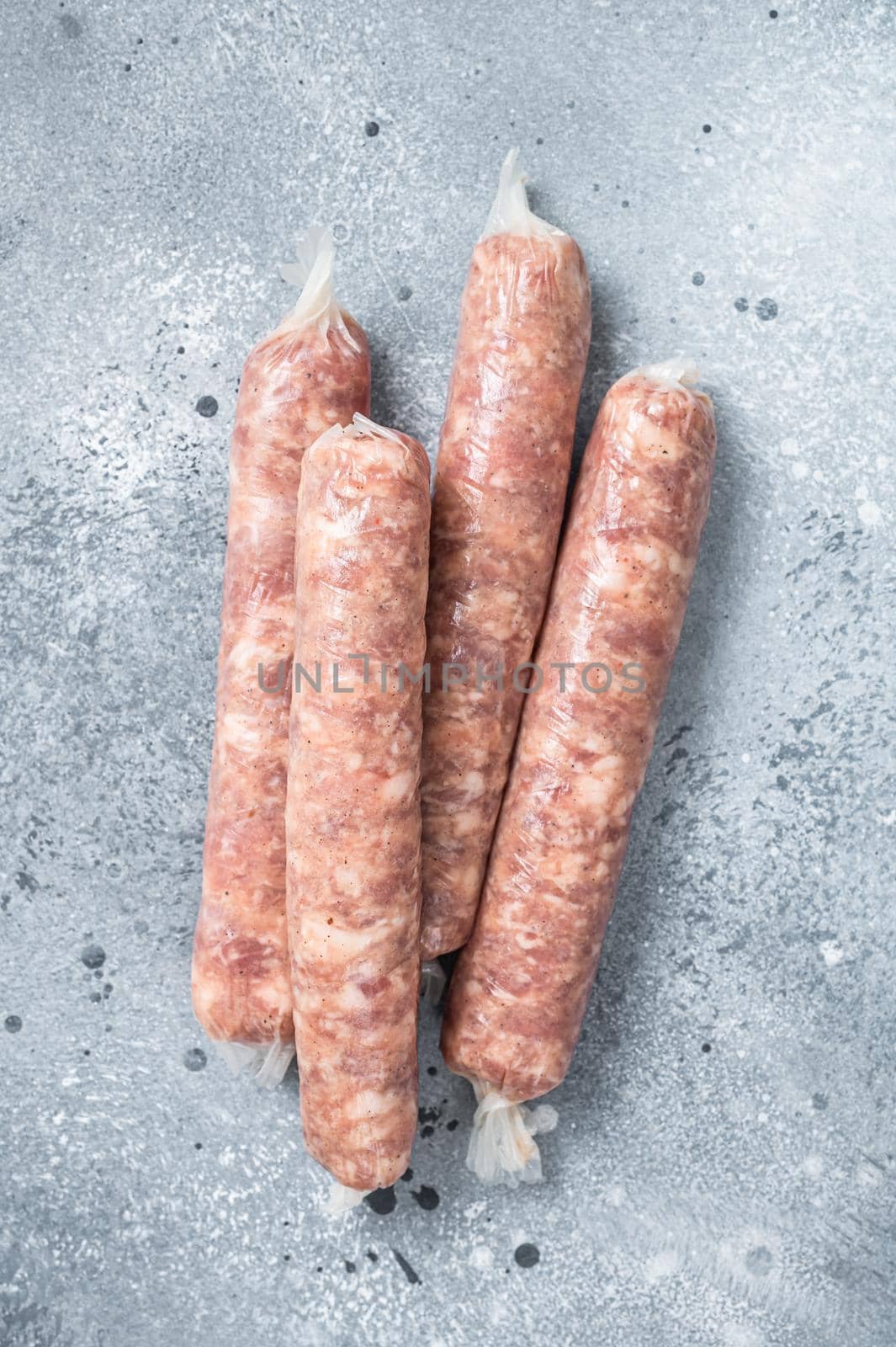 Bratwurst raw sausages on a kitchen table. Gray background. Top view by Composter