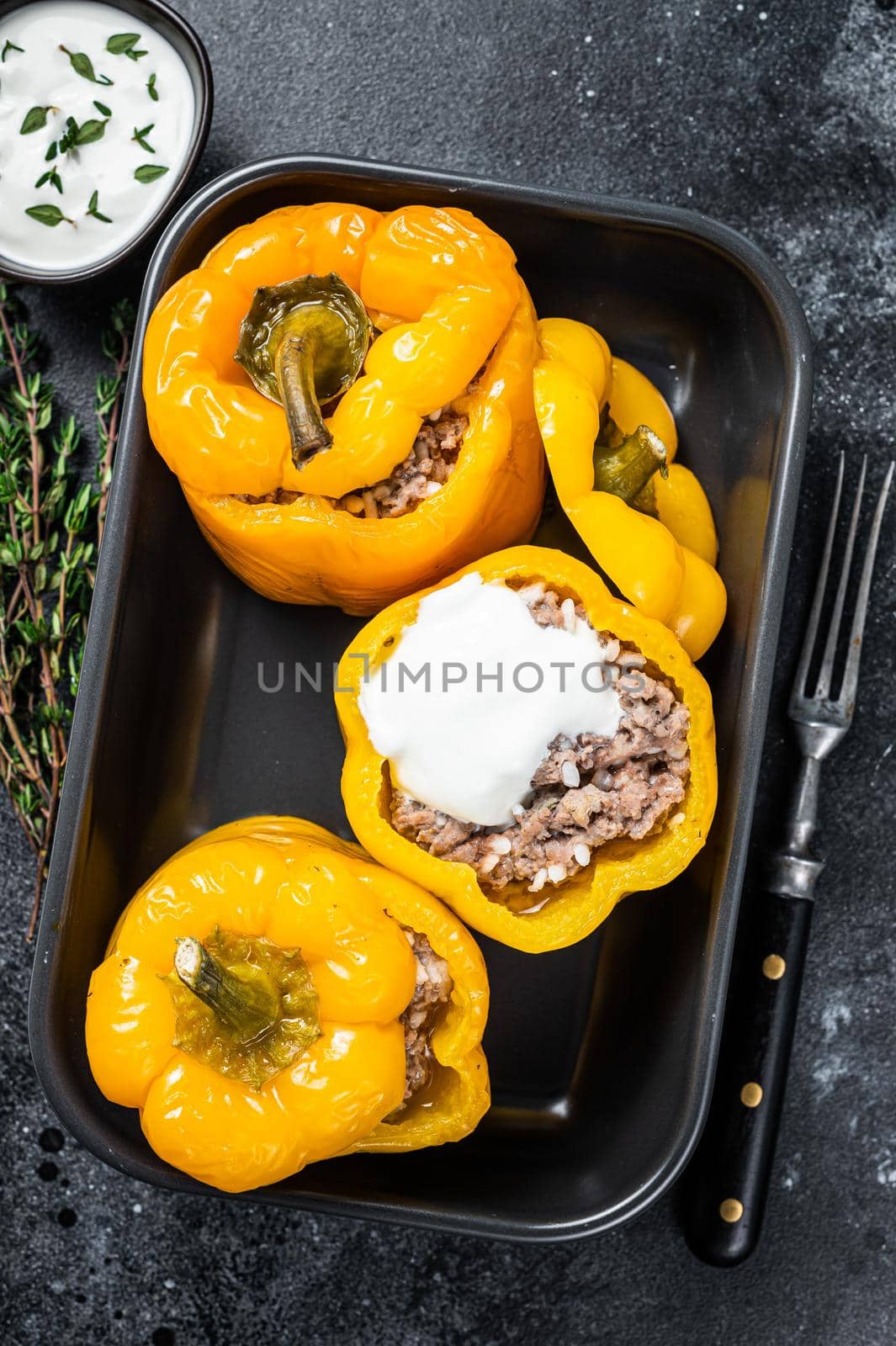 Baked yellow Sweet bell pepper stuffed with beef meat, rice and vegetables. Black background. Top view.