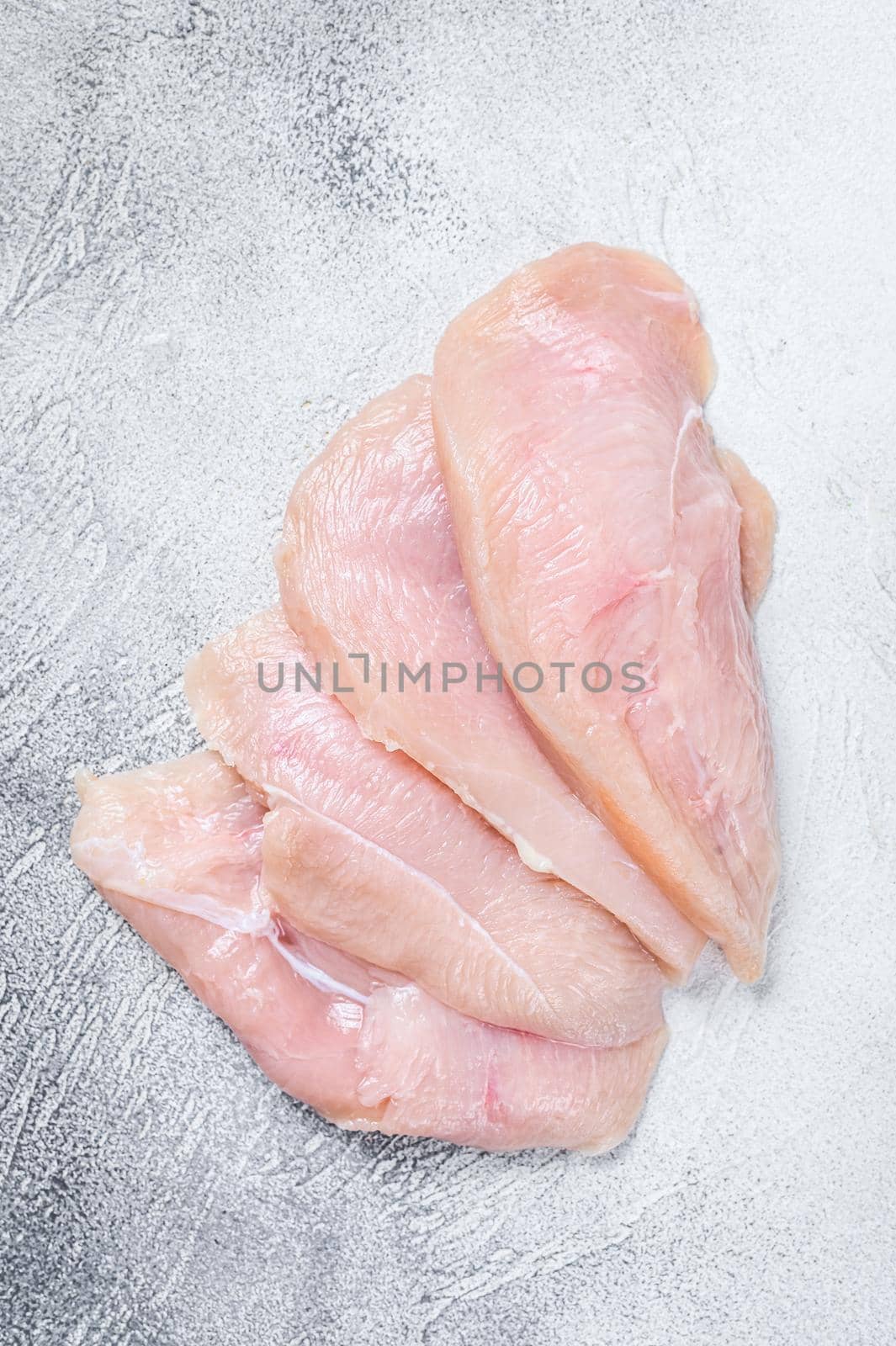 Raw sliced chicken breast fillet steaks. White background. Top view. by Composter