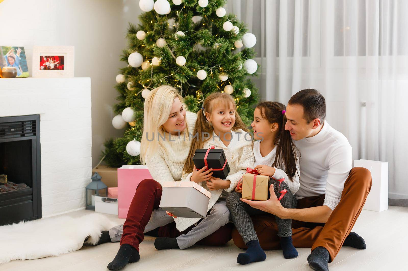 happy young family holding christmas gift and smiling at camera by Andelov13
