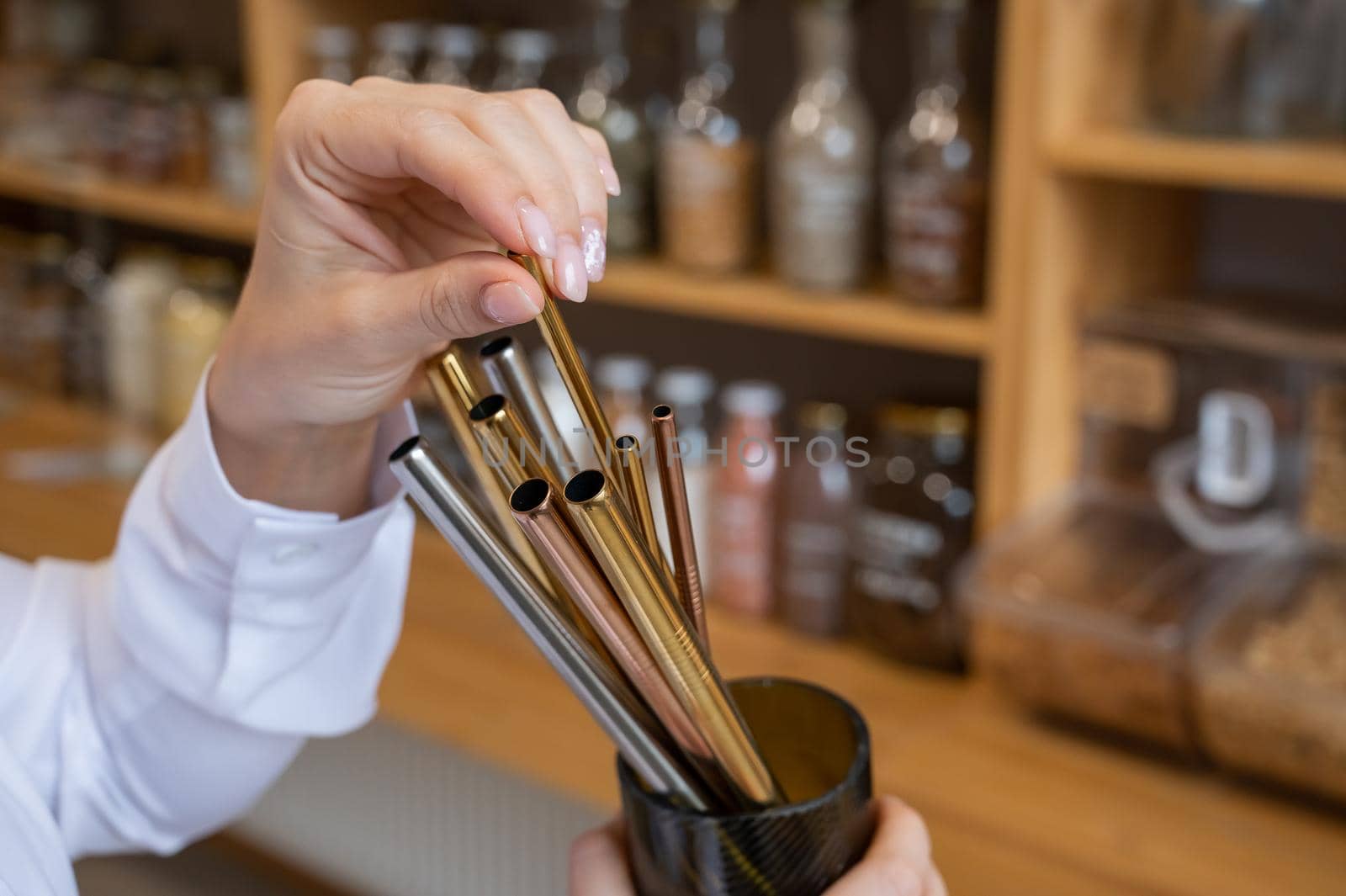 A woman holds a jar of reusable steel tubes. Eco concept.