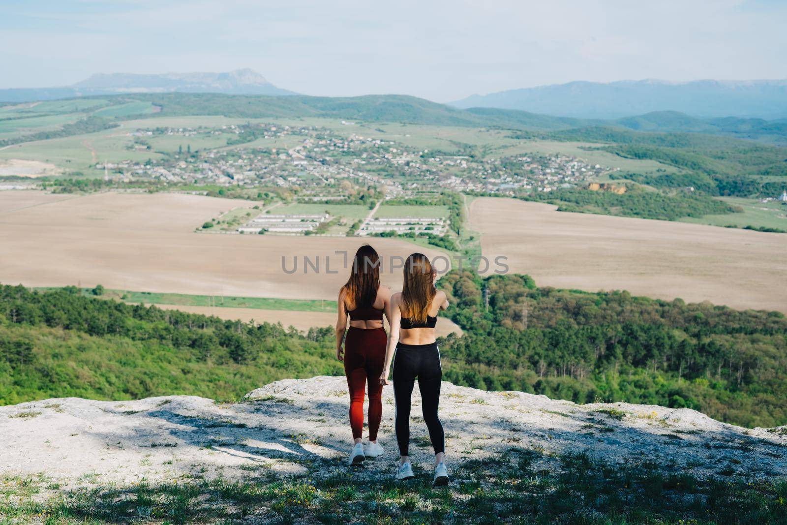 Two girls play sports on a cliff. Yoga in nature. by Rodnova