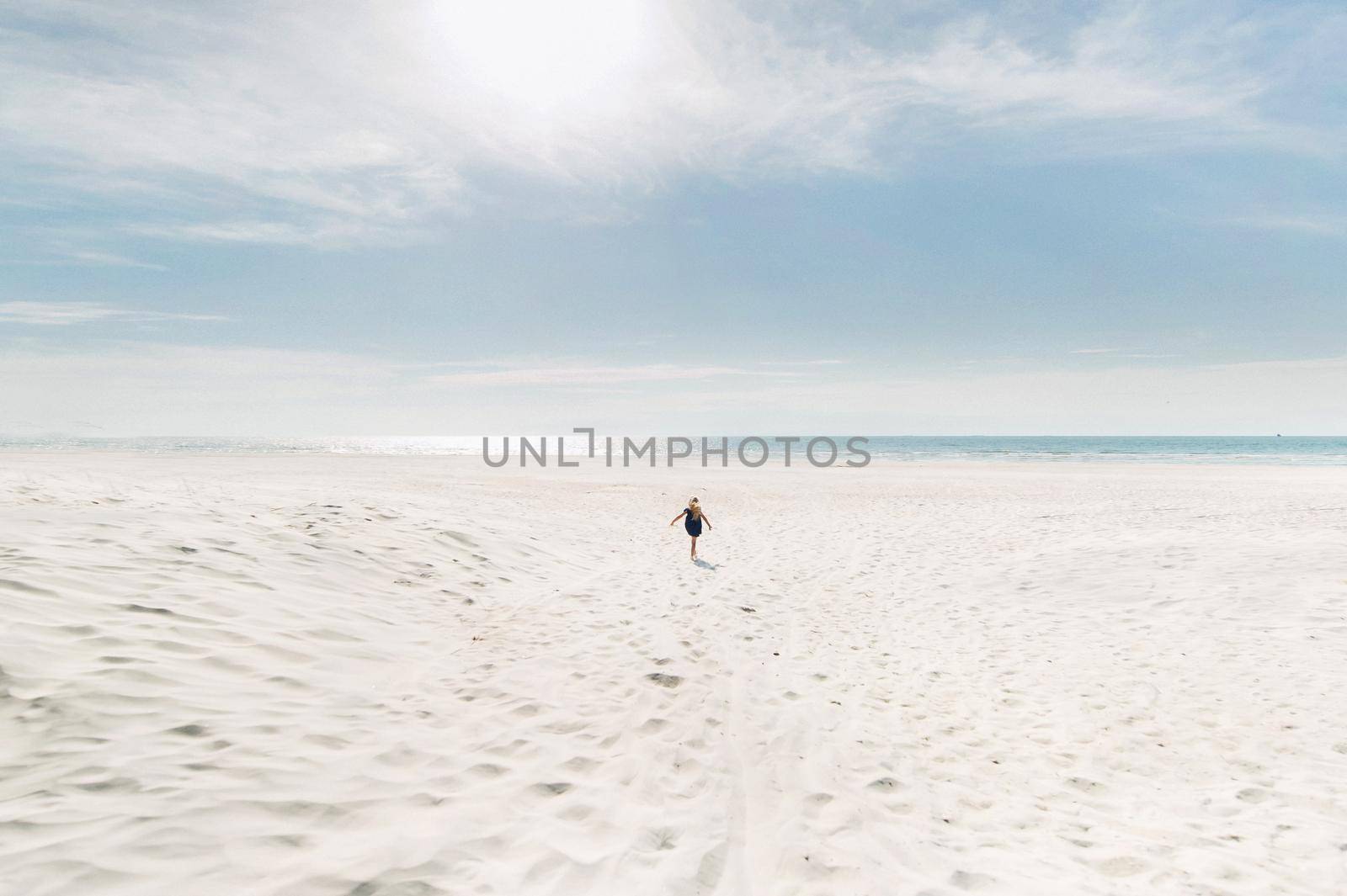 a child runs along a white beach to the Baltic sea in Sunny weather.A little girl runs across the snow-white sand to meet the sea.Lithuania.