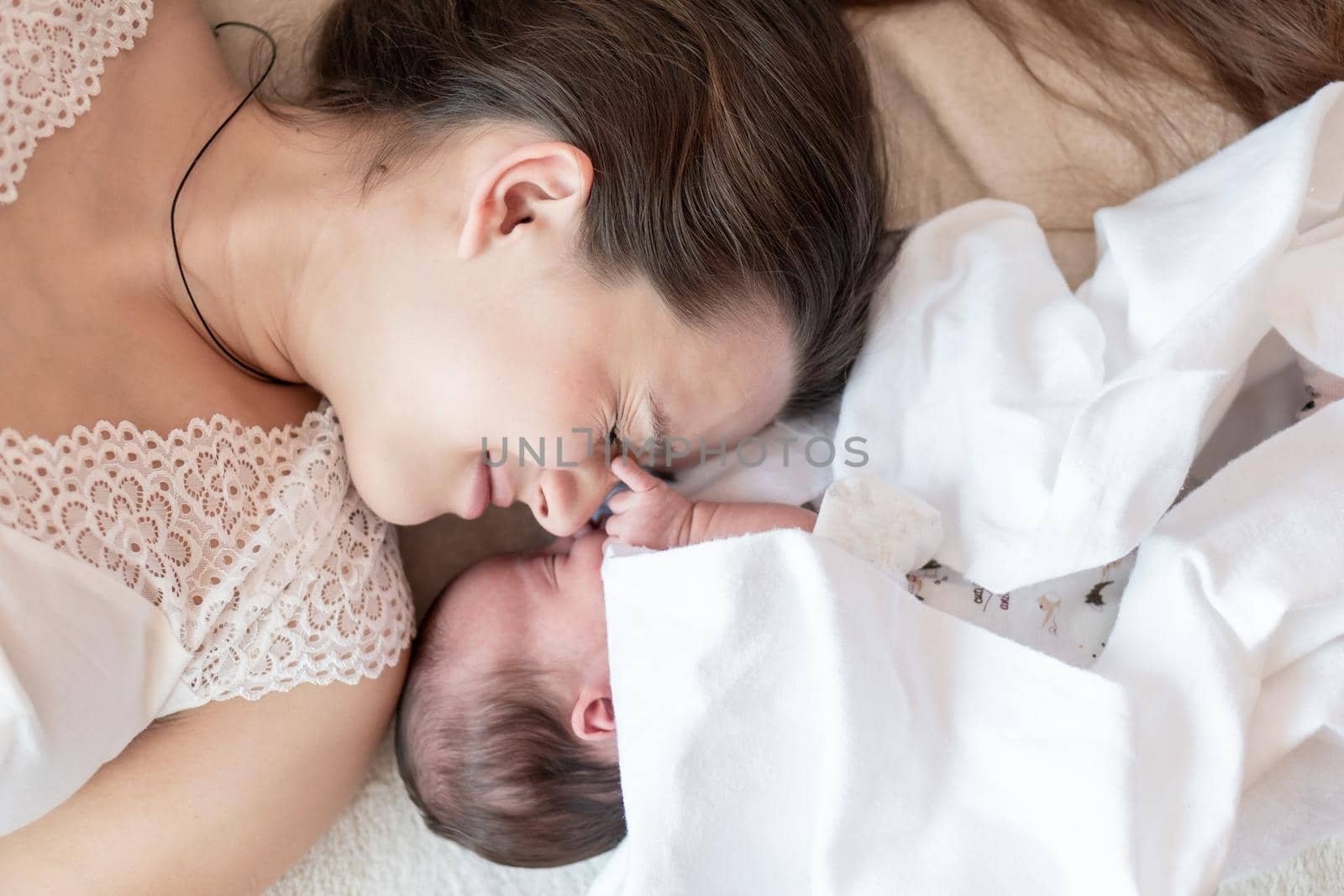 motherhood, infancy, childhood, family, care, medicine, sleep, health, maternity concept - portrait of mom with newborn baby wrapped in diaper on white background, place for text, close-up, soft focus.