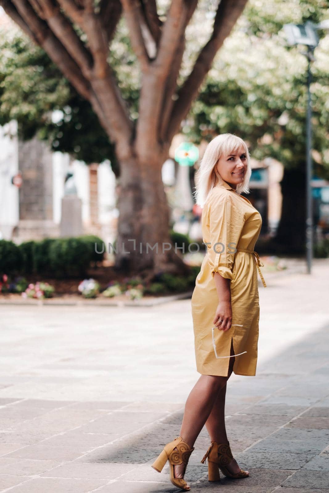 a blonde woman in a yellow summer dress stands on the street of the Old town of La Laguna on the island of Tenerife.Spain, Canary Islands.