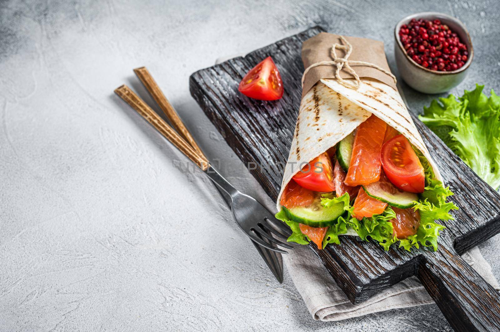 Wrap sandwich, roll with fish salmon and vegetables. White background. Top view. Copy space.