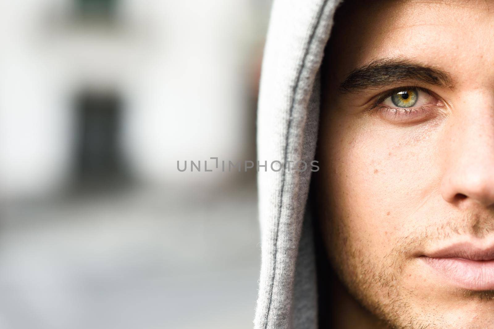 Handsome young man with blue eyes in urban background by javiindy