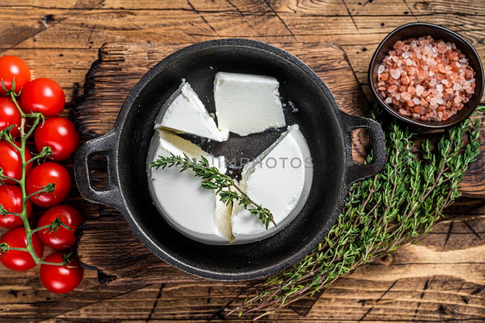 Fresh Ricotta cream Cheese in a pan with basil and tomato. wooden background. Top view.