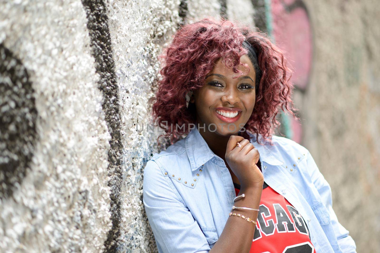 Portrait of beautiful black woman in urban background with red hair