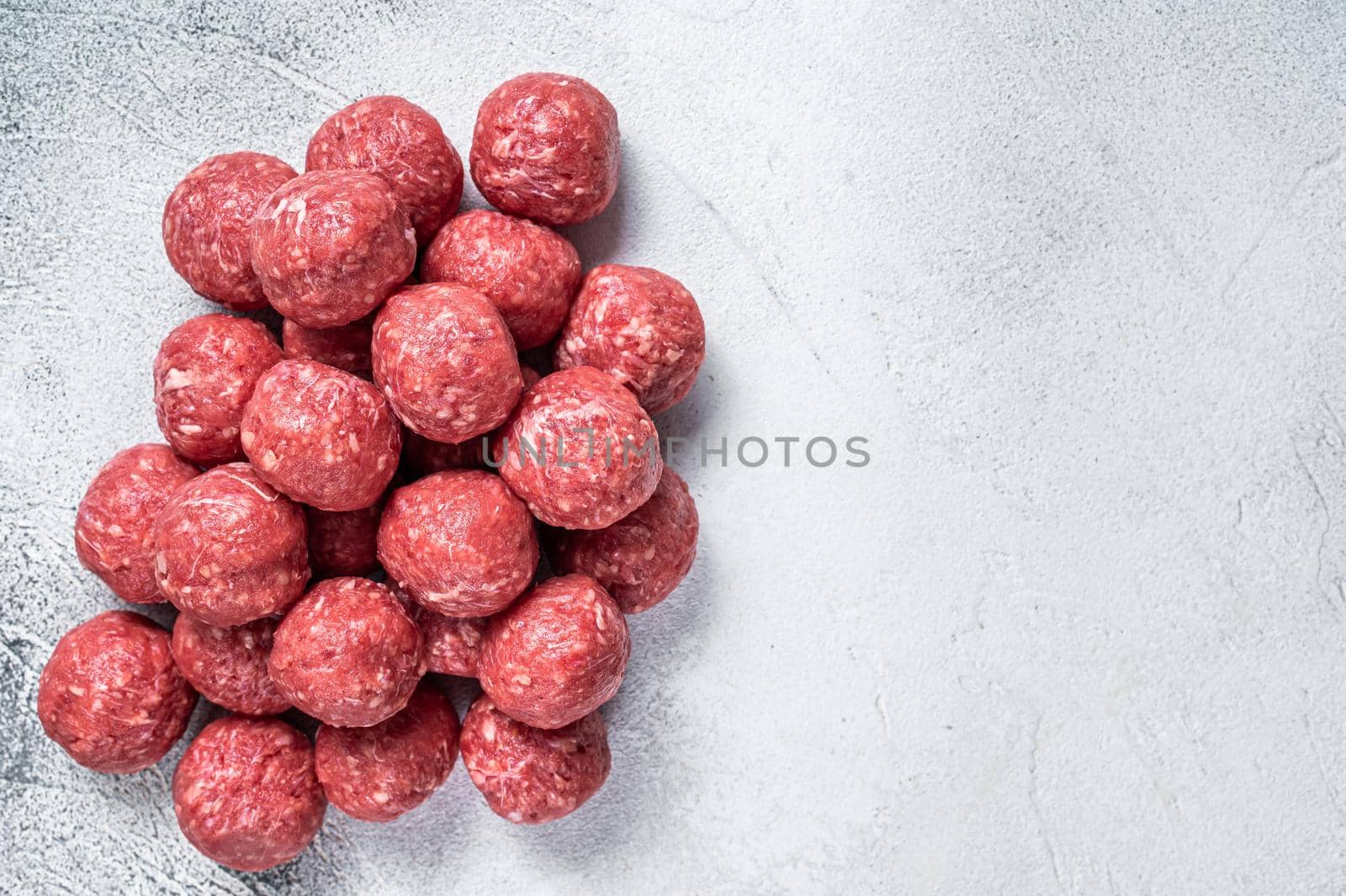 Raw beef and pork meatballs with spices on kitchen table. White background. Top view. Copy space by Composter