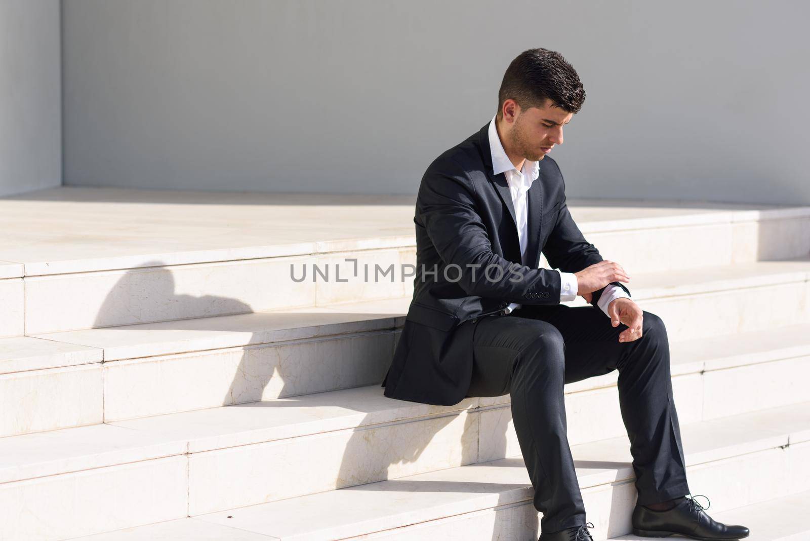 Young businessman near a office building wearing black suit by javiindy