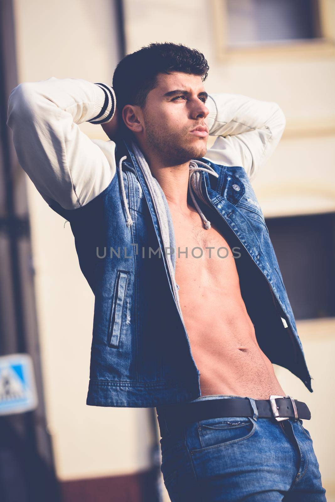 Handsome young man with blue eyes posing in urban background by javiindy