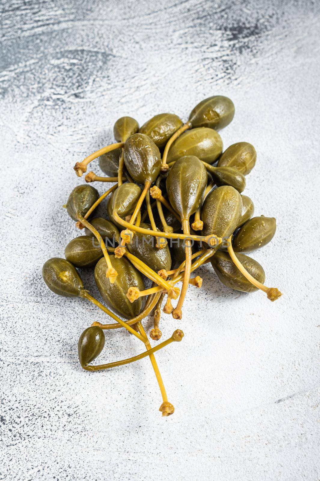 Pickled capers on a kitchen table. White background. Top view.