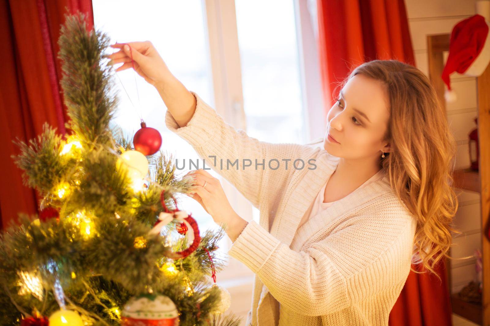 Christmas holiday and New Year concept. Cheerful woman decorating Christmas tree at home.