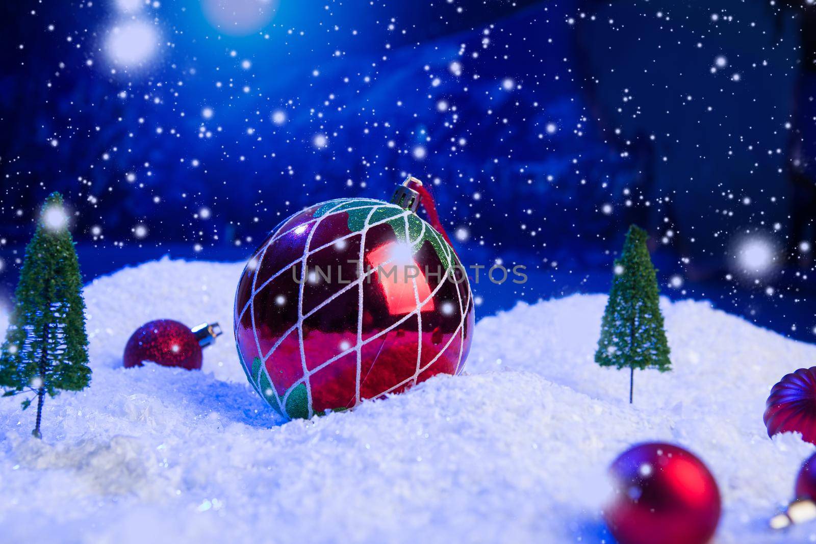 Christmas background with Christmas balls on snow over fir-tree, night sky and moon. Shallow depth of field. Christmas background. Fairy tale. Macro. Artificial magic dreamy world. .