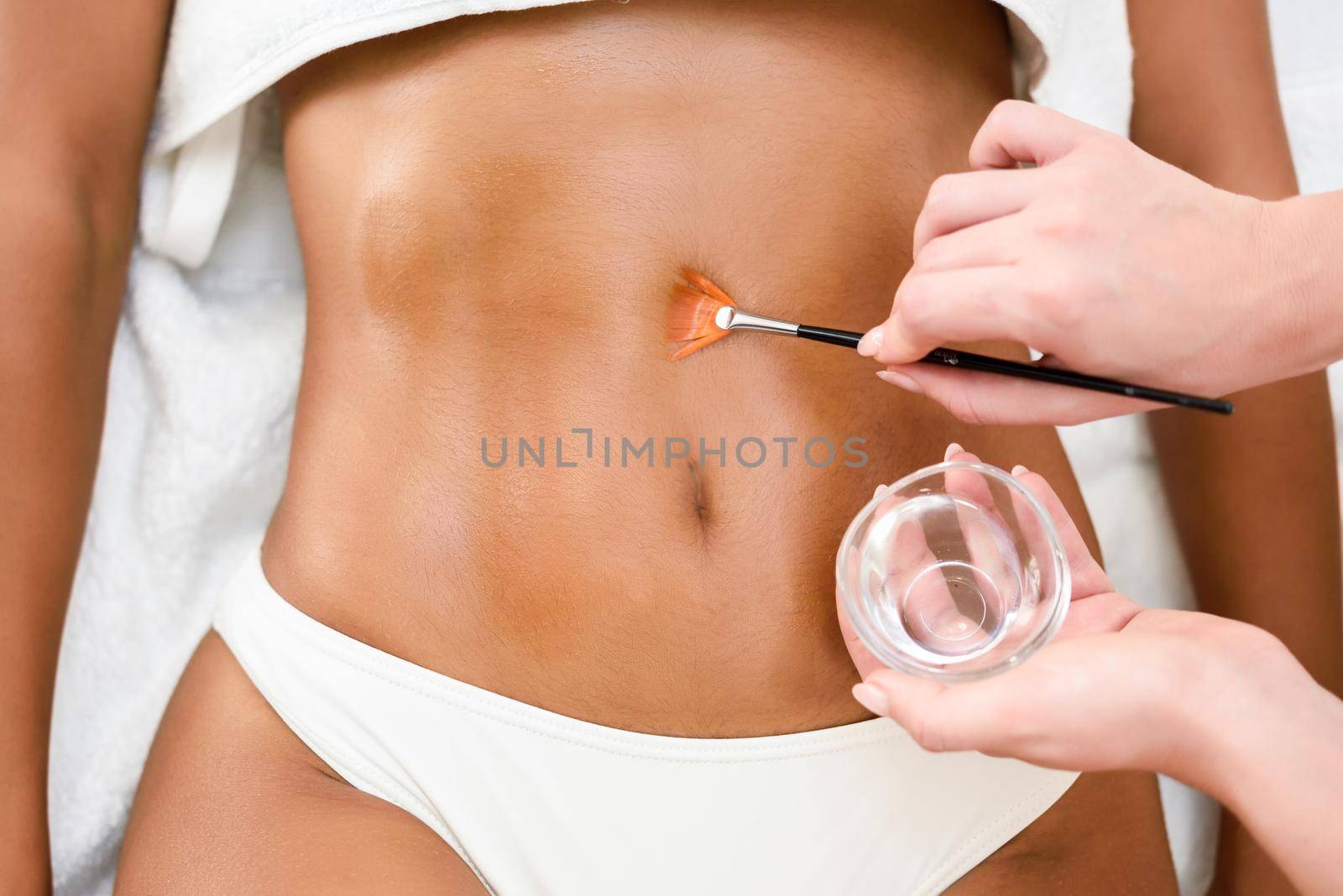 Woman receiving belly massage treatment with oil brush by javiindy