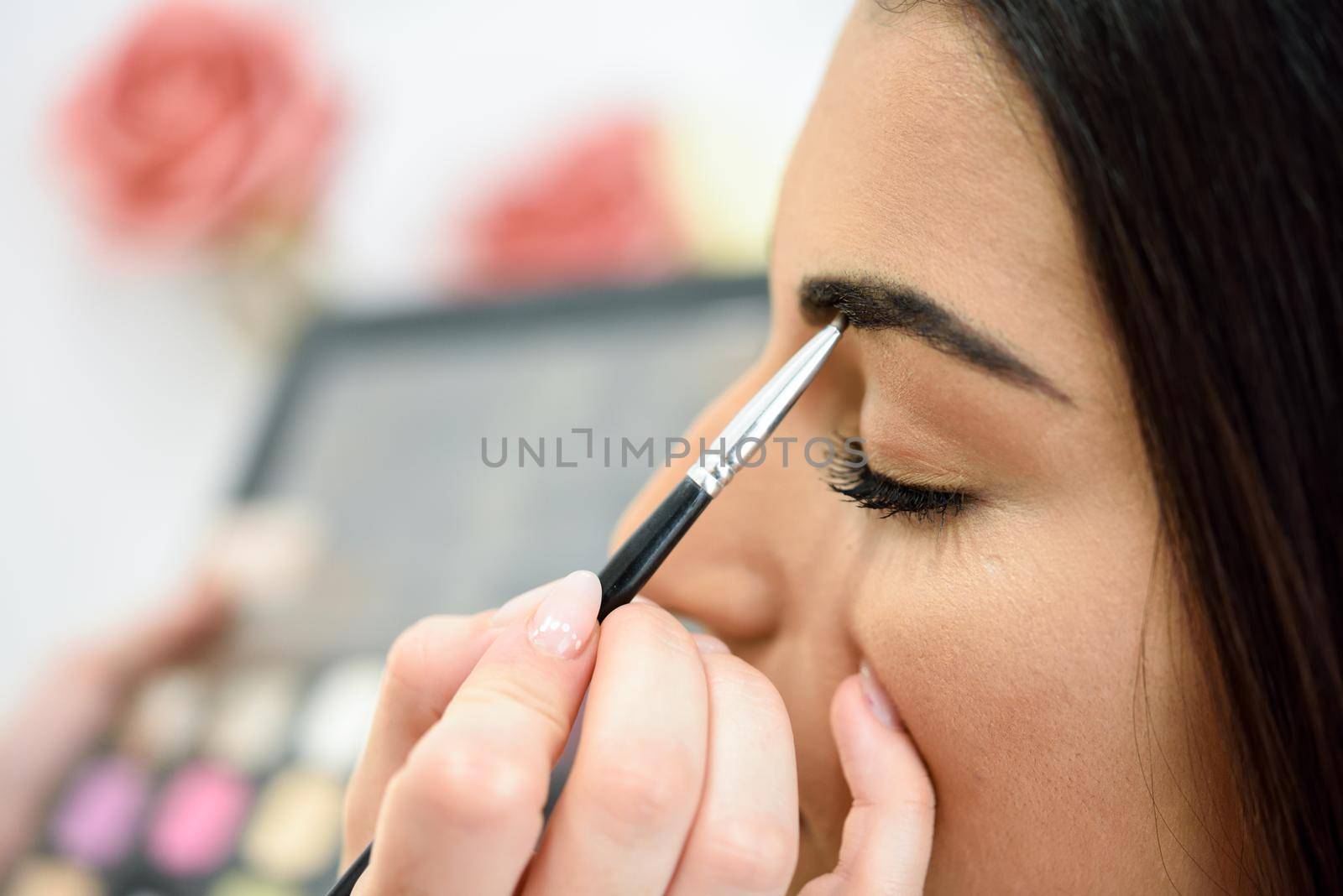 Makeup artist putting make-up on an woman's eyebrows by javiindy