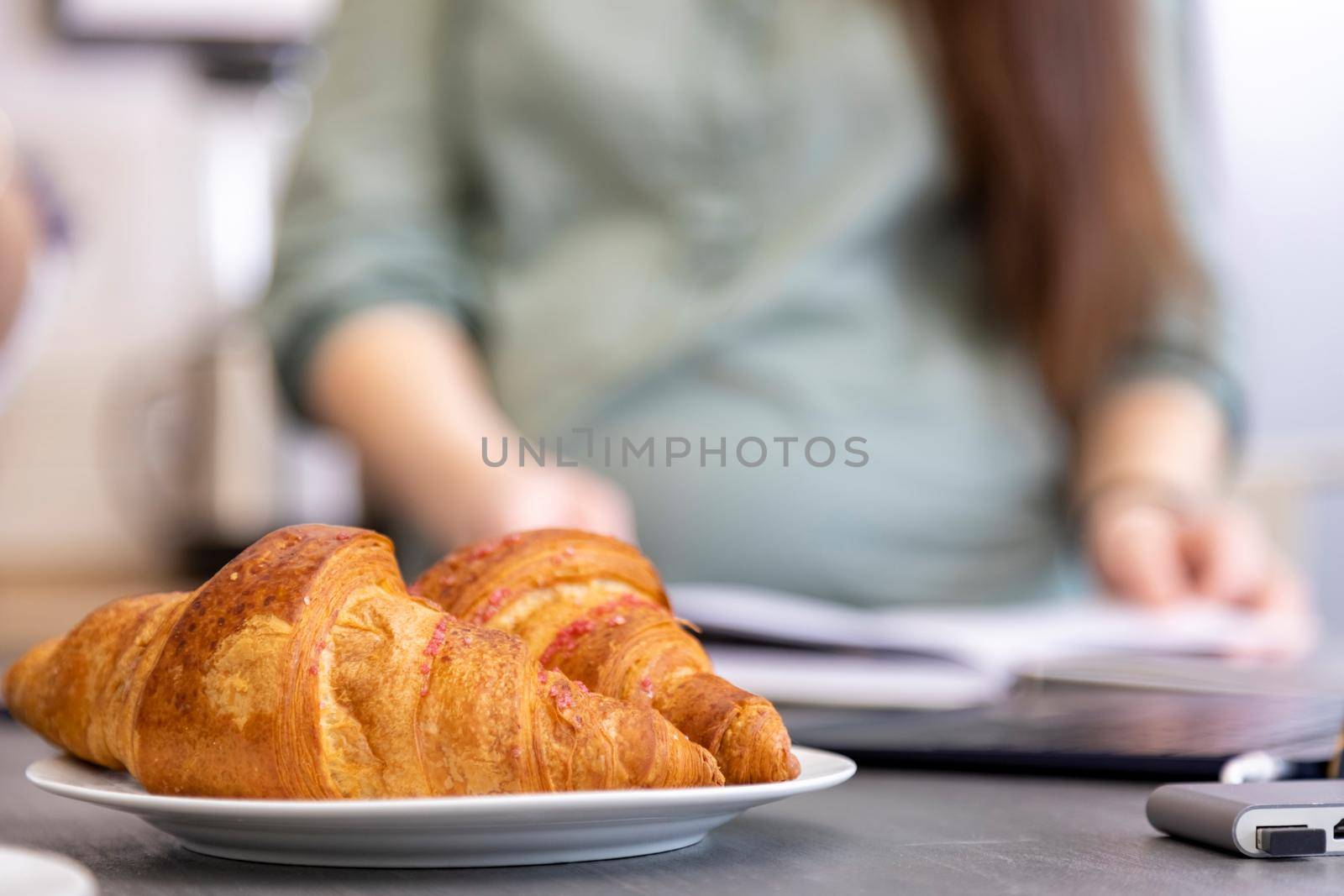 fresh croissants on the background of a pregnant woman in a blur. no face. pregnant women diet food concept. gluten free food by Mariaprovector