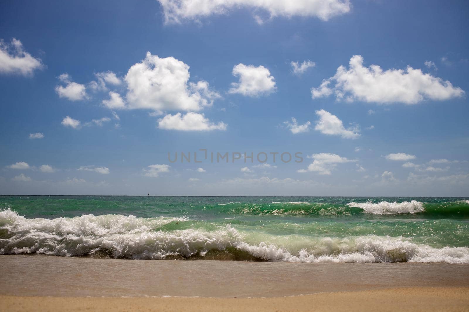 strong waves on beautiful sea sandy beach with blue cloudy sky