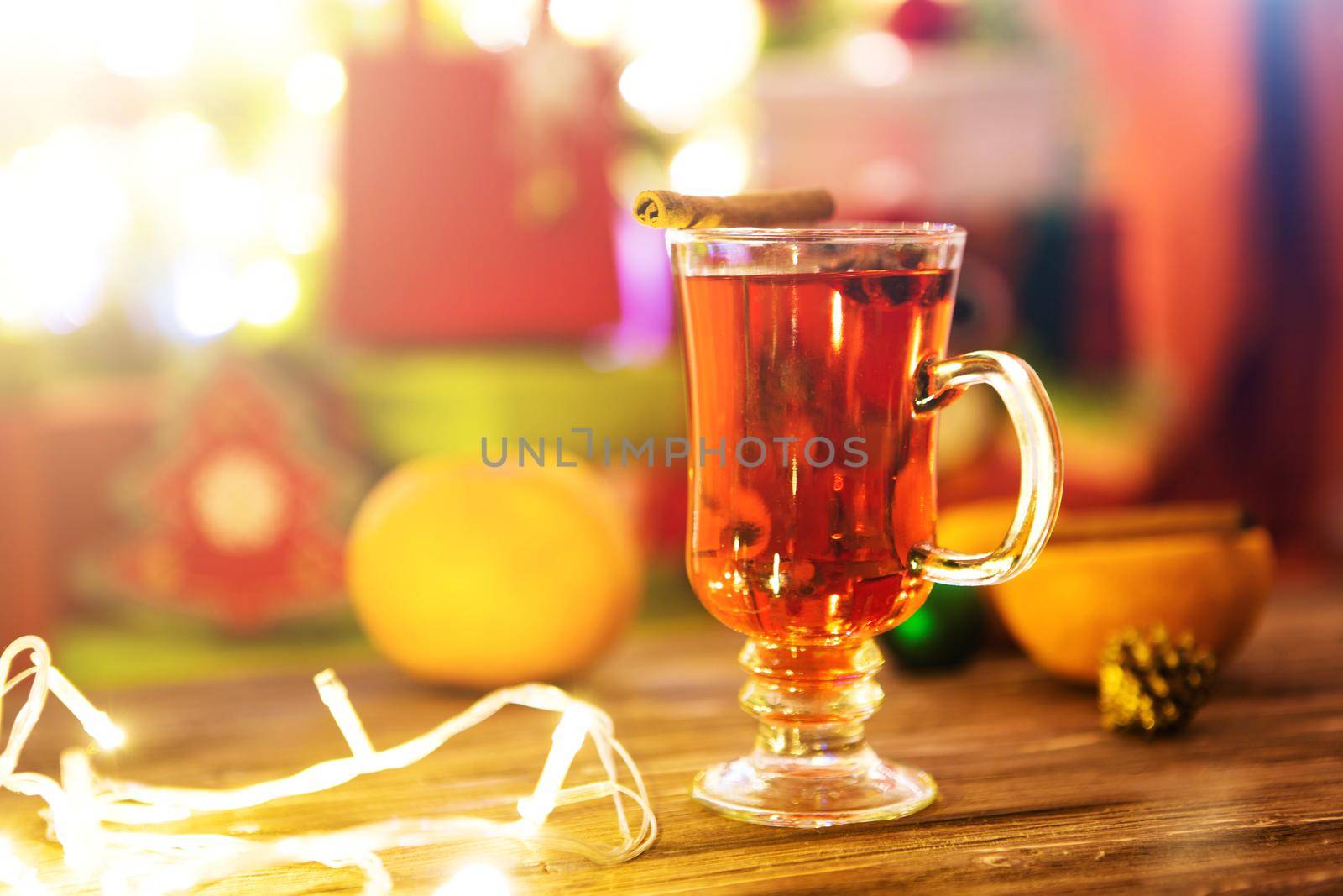 Mulled wine with spices and Christmas tree on wooden background.