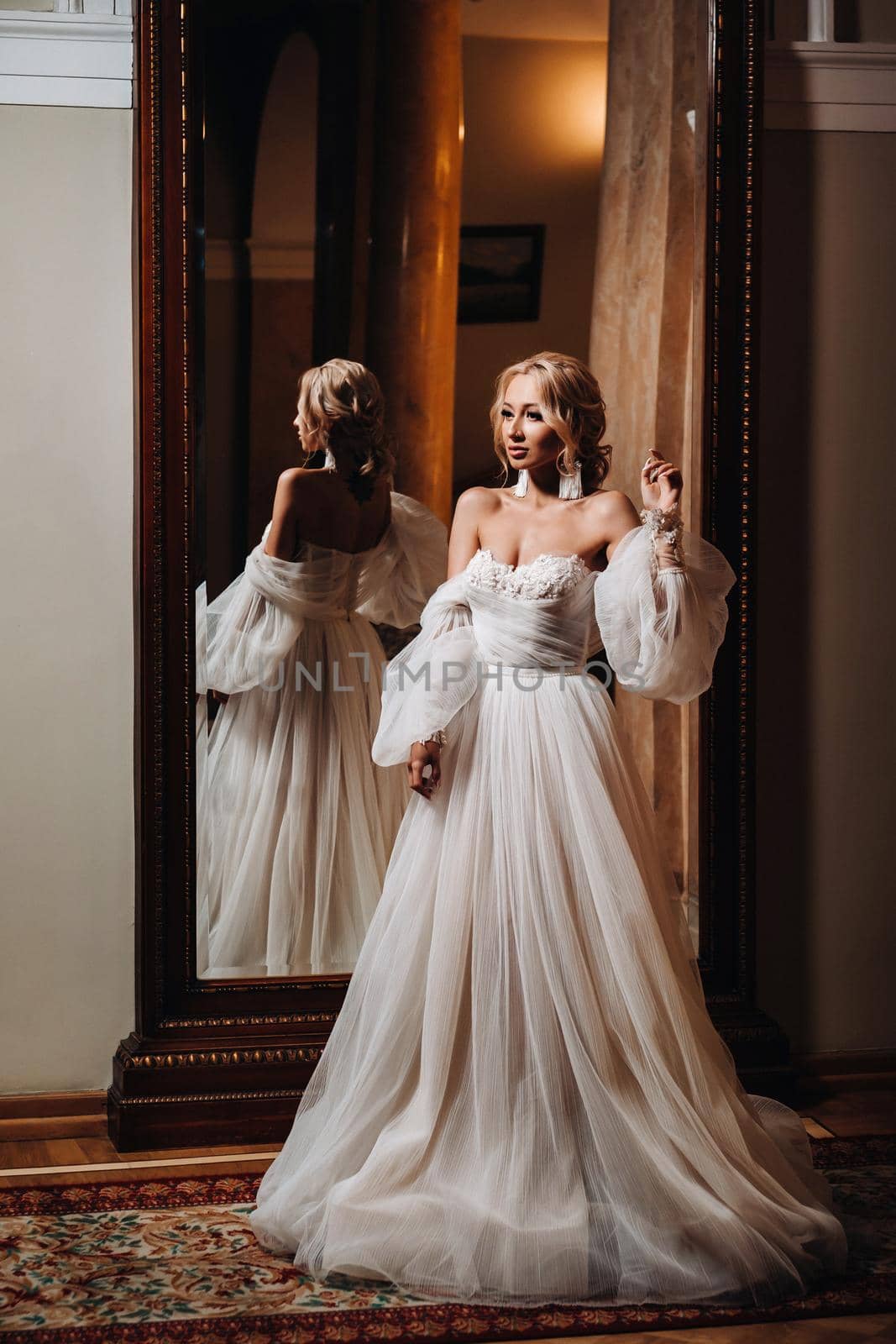 Portrait of a beautiful bride standing with her back to the mirror by Lobachad