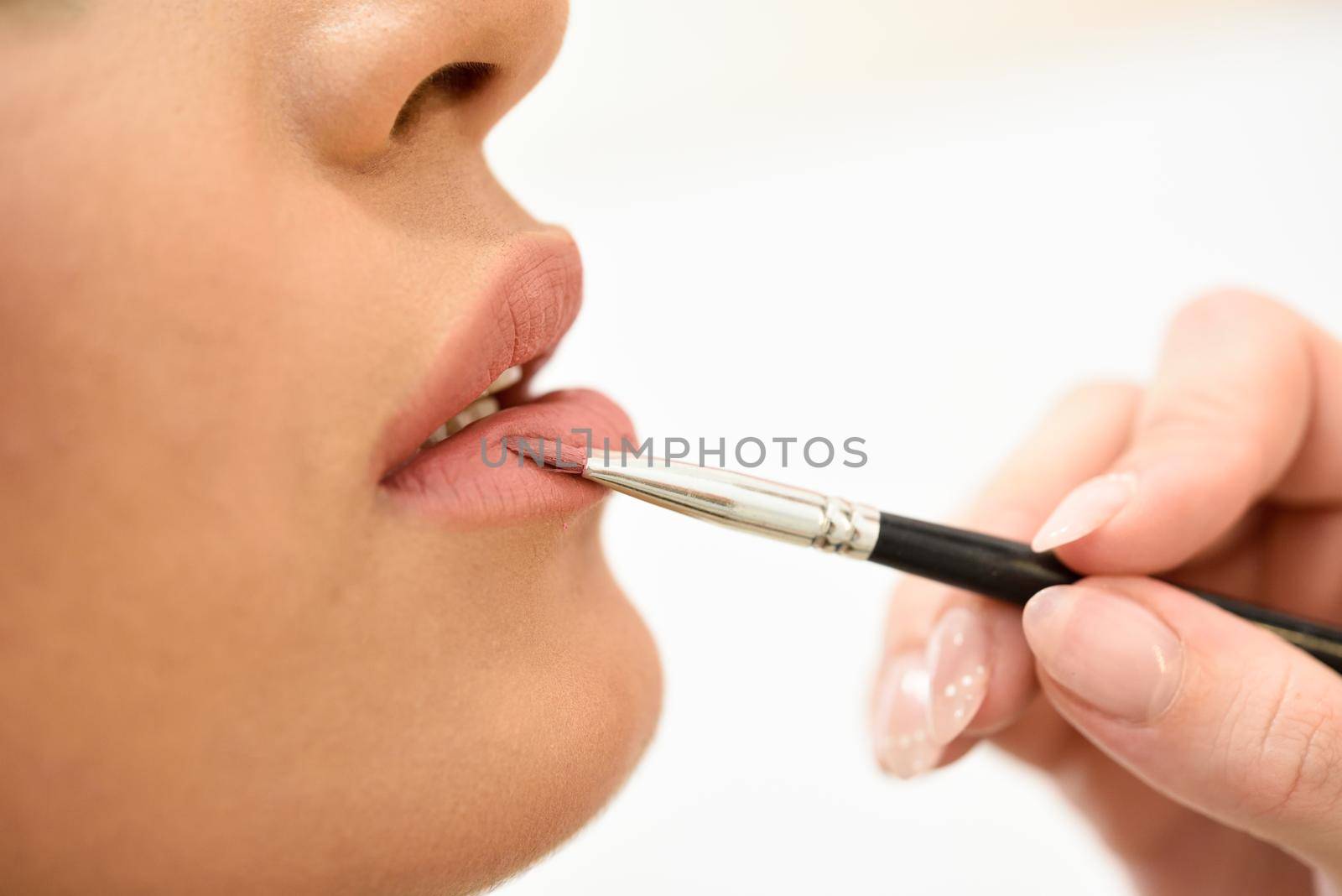 Makeup artist making up lips of an African young woman by javiindy