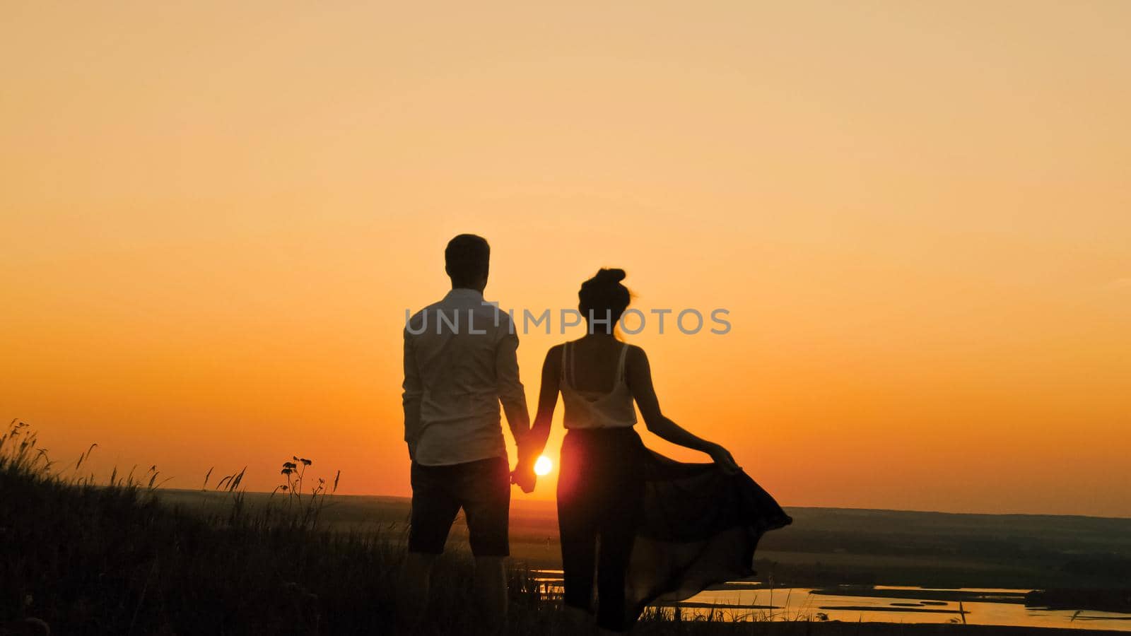 Young loving couple - brave man and beautiful girl at dusk silhouette, looking to sun by Studia72