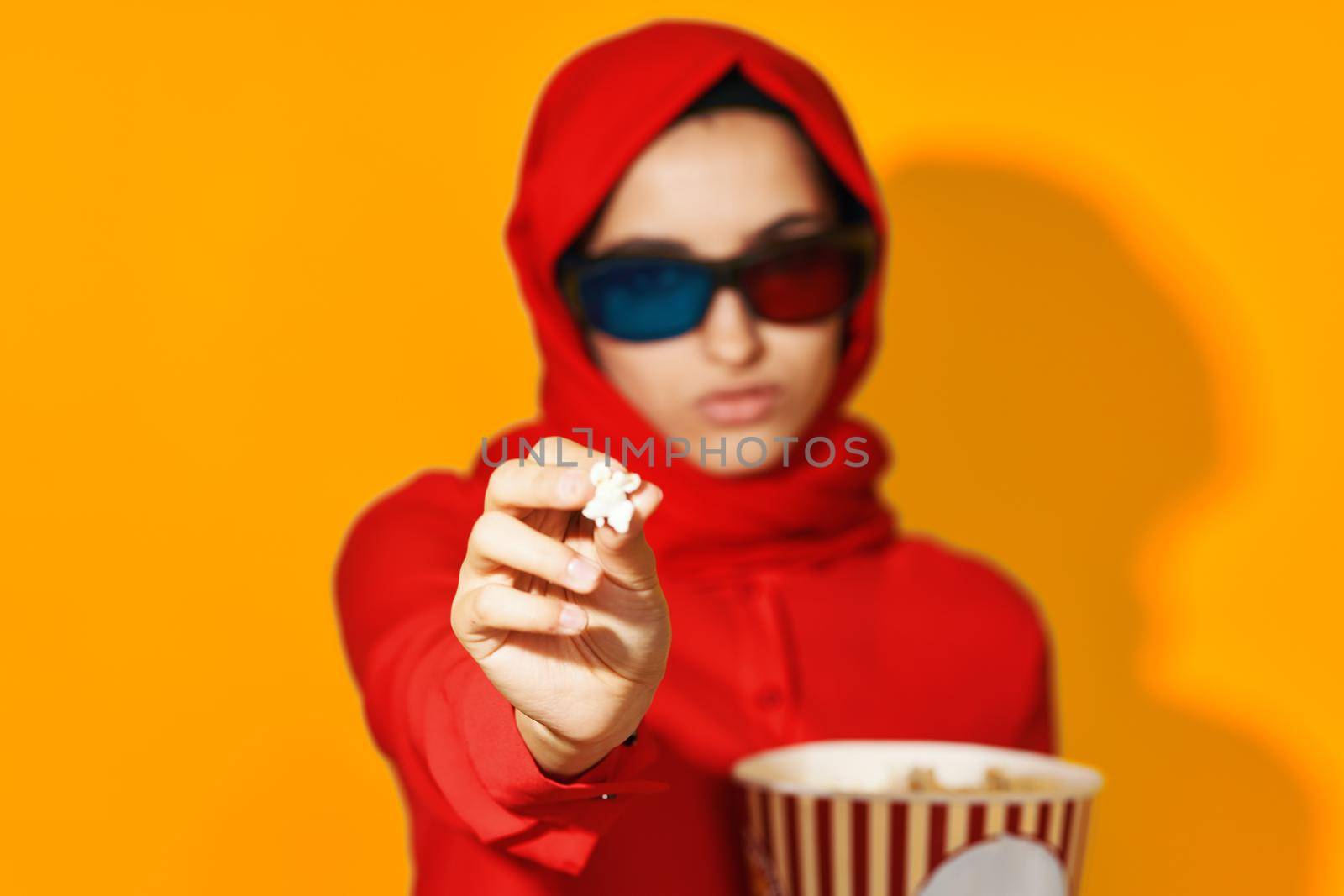 woman in red hijab 3d glasses technology watching movie popcorn yellow background. High quality photo