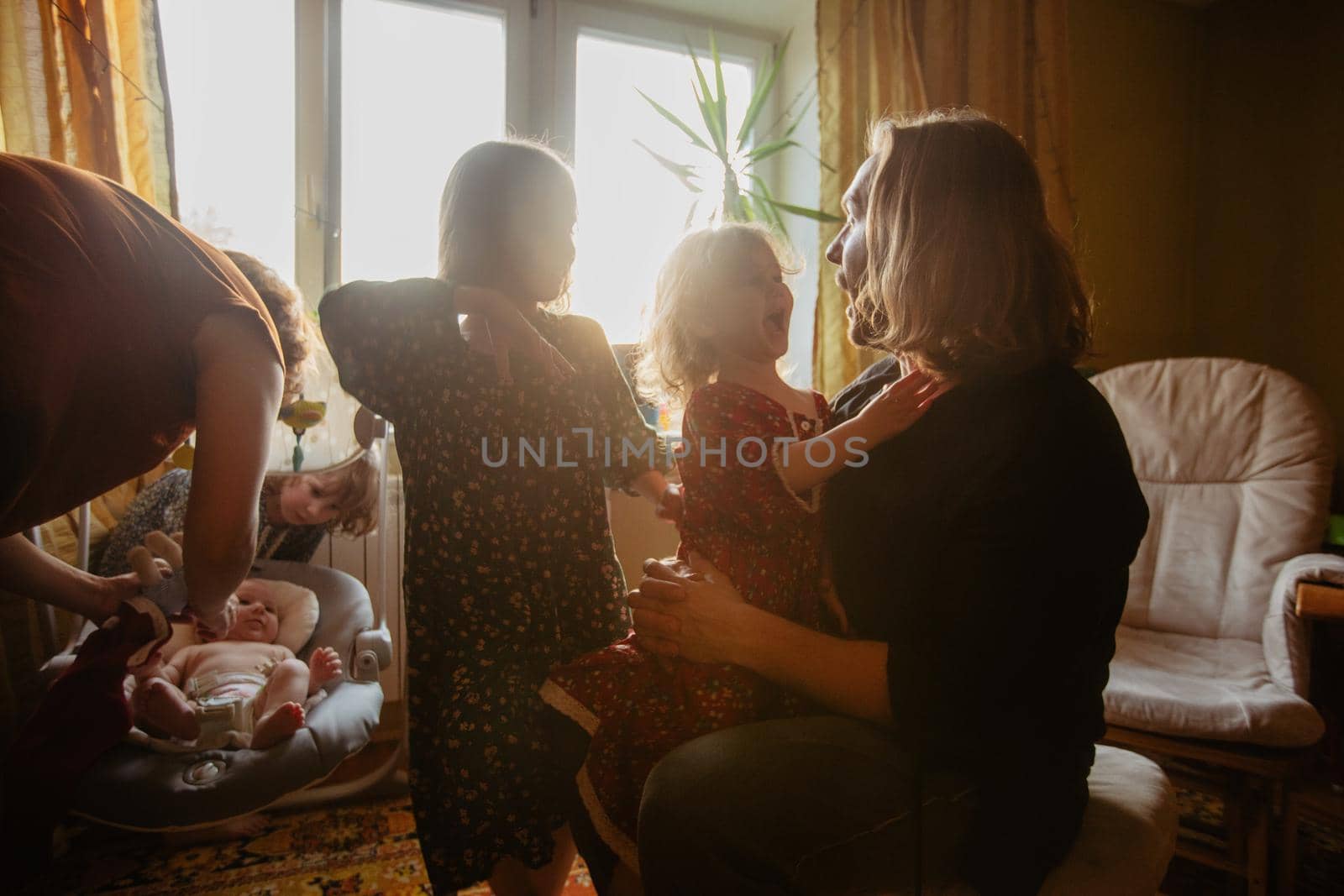 Cheerful mother and father playing with cute siblings while having fun together in room at home