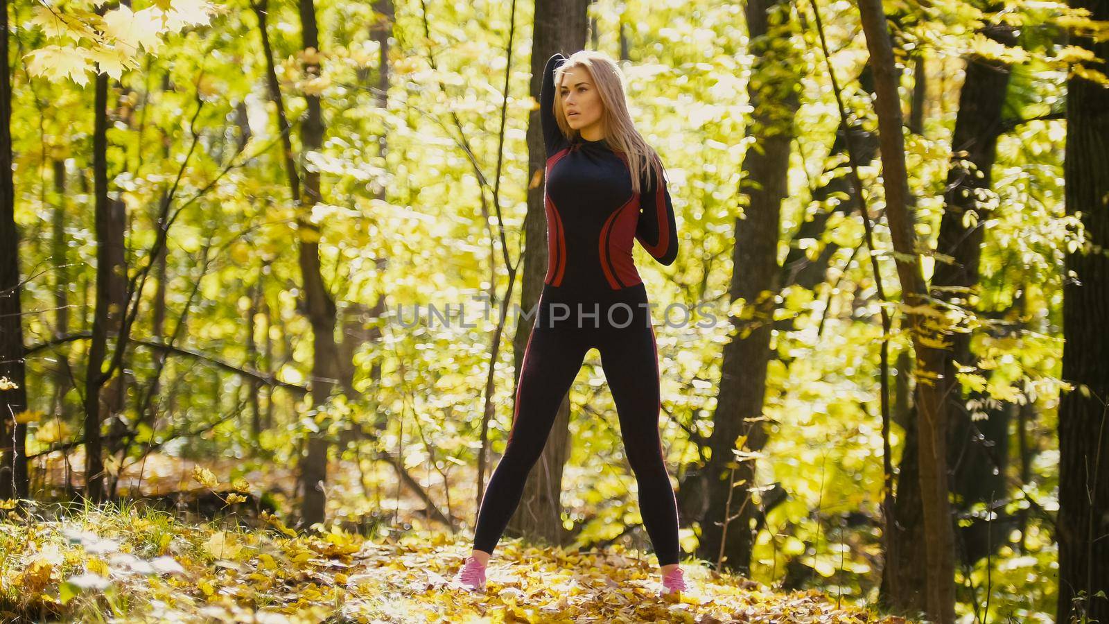Woman doing fitness exercises outdoor. Female stretching her loin in autumn forest. Slim girl at workout by Studia72