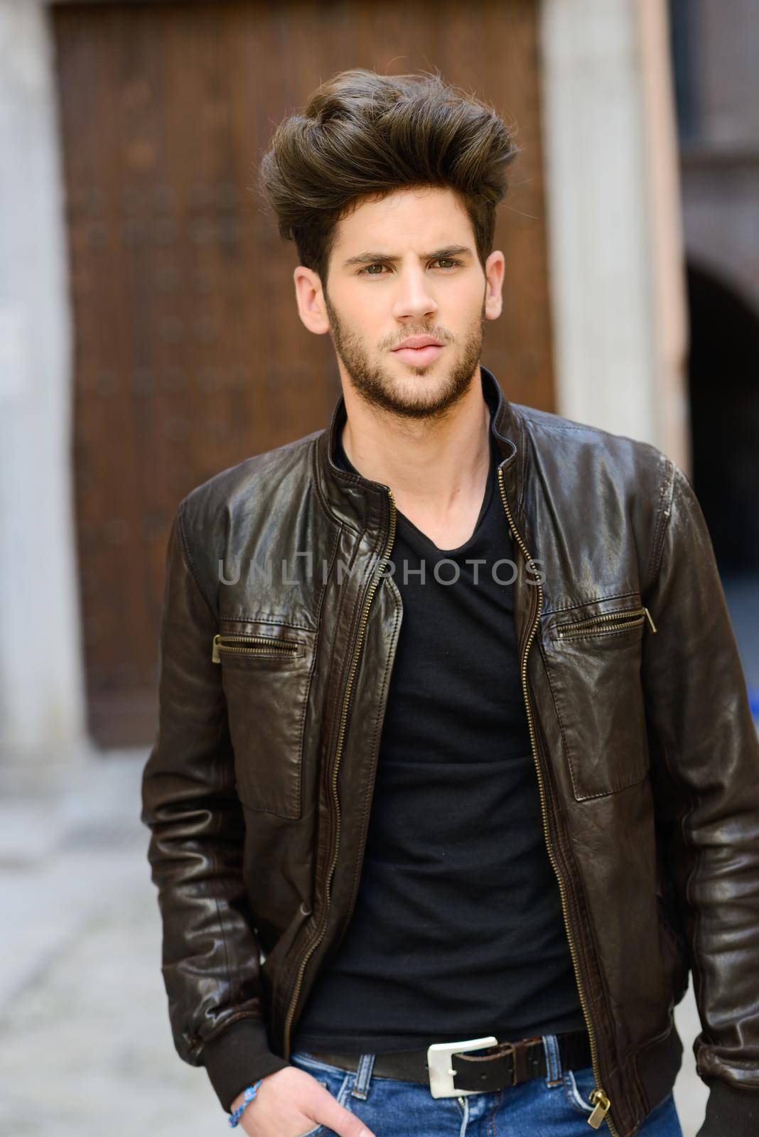 Portrait of a young handsome man, model of fashion, with modern hairstyle in urban background