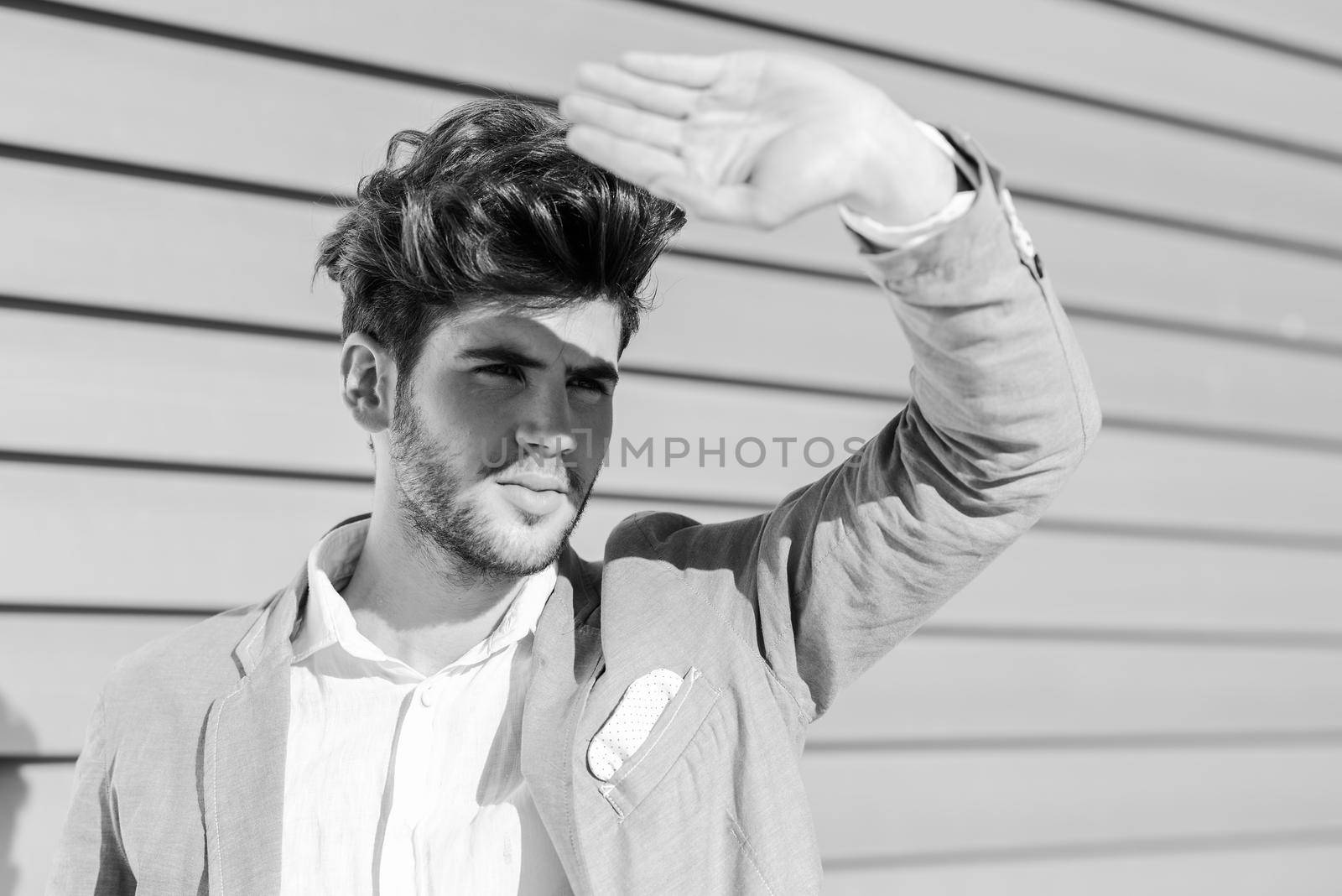 Portrait of a young handsome man, model of fashion, with modern hairstyle in urban background wearing blue blazer jacket