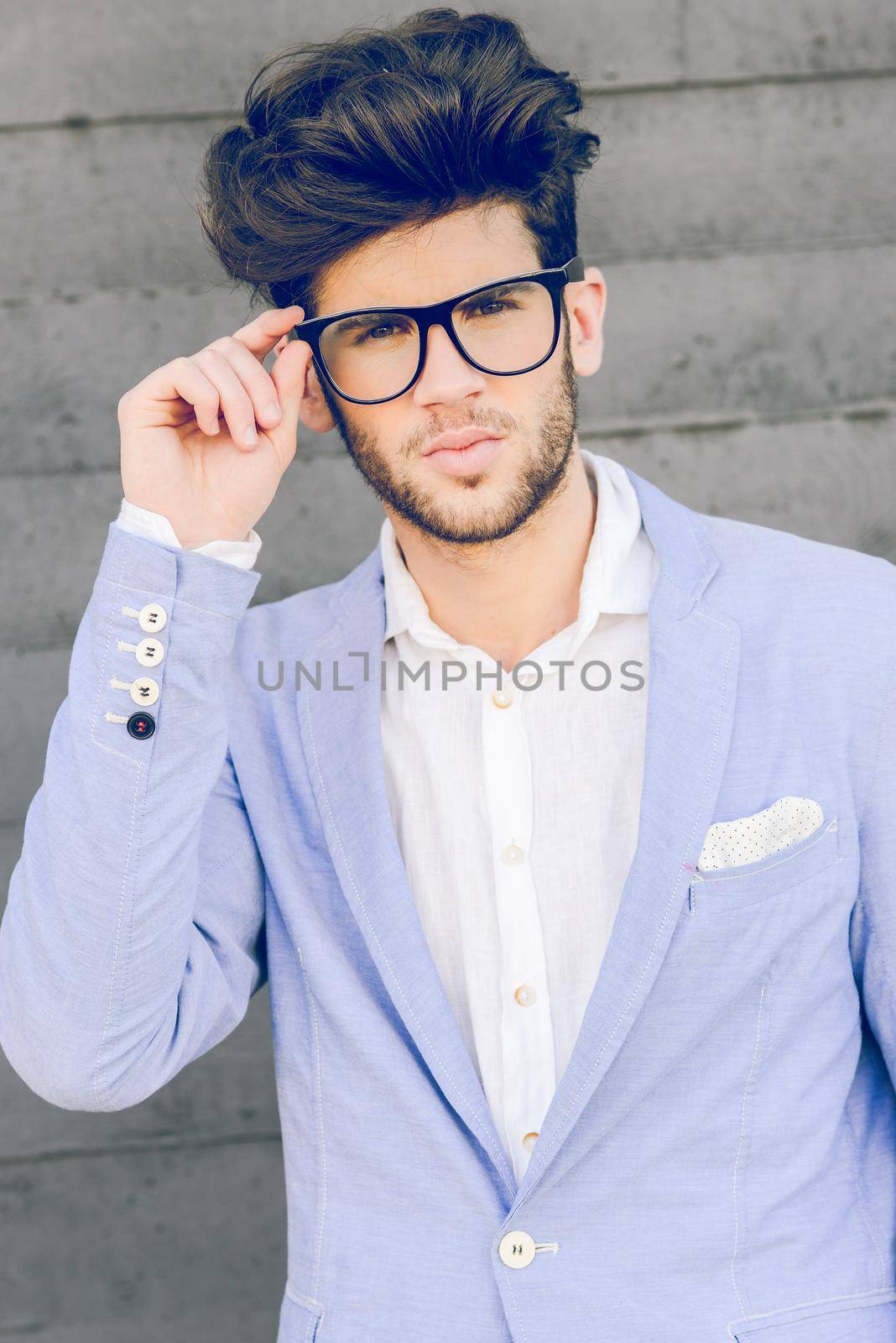 Portrait of cheerful trendy guy with black eyeglasses on wearing blue blazer jacket