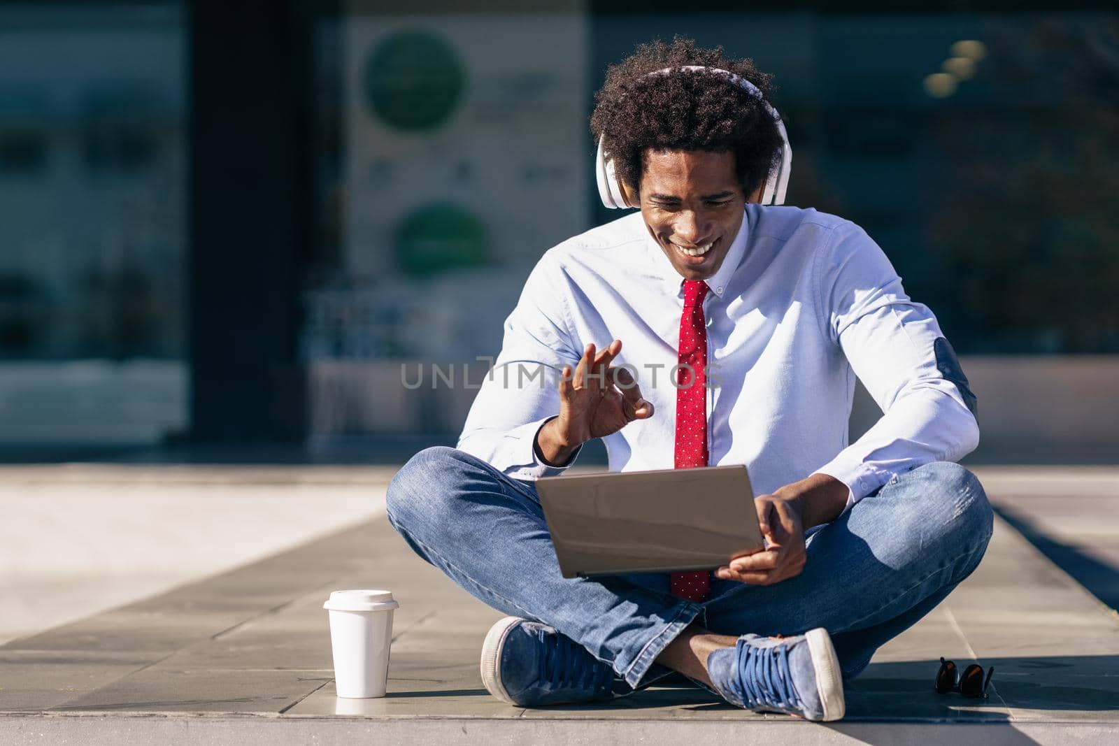 Black Businessman using laptop computer and headphones by javiindy