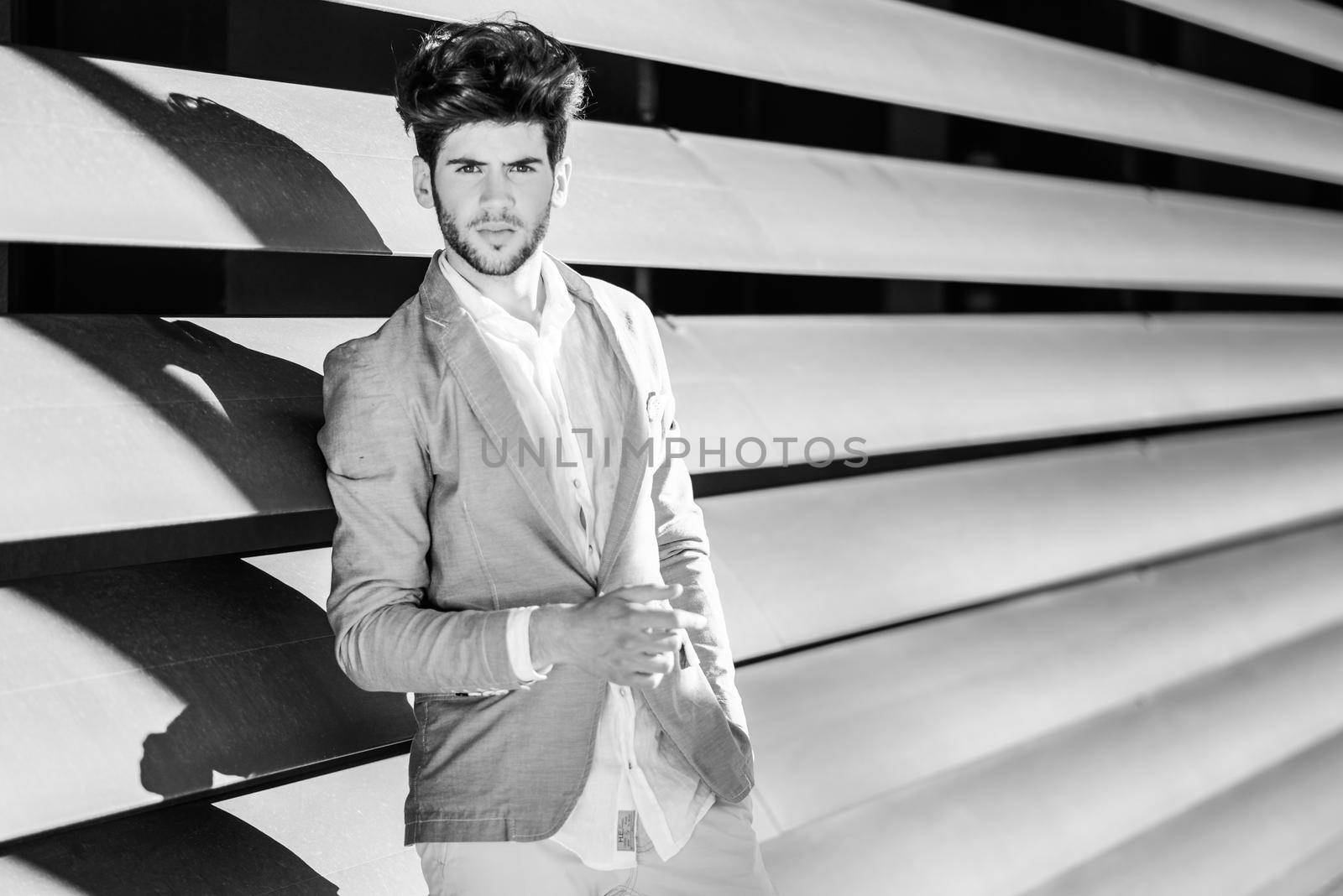 Portrait of a young handsome man, model of fashion, with modern hairstyle in urban background wearing blue blazer jacket