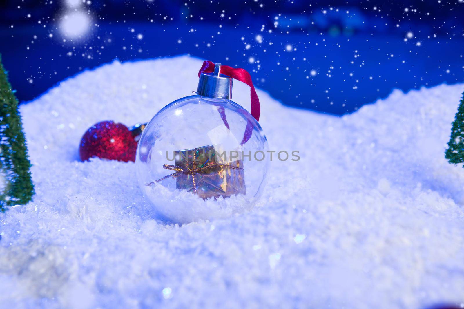Christmas background with Christmas balls on snow over fir-tree, night sky and moon. Shallow depth of field. Christmas background. Fairy tale. Macro. Artificial magic dreamy world. .