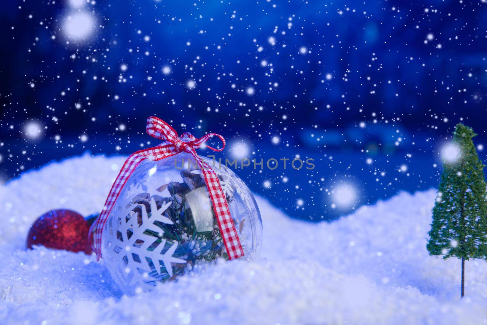 Christmas background with Christmas balls on snow over fir-tree, night sky and moon. Shallow depth of field. Christmas background. Fairy tale. Macro. Artificial magic dreamy world. .