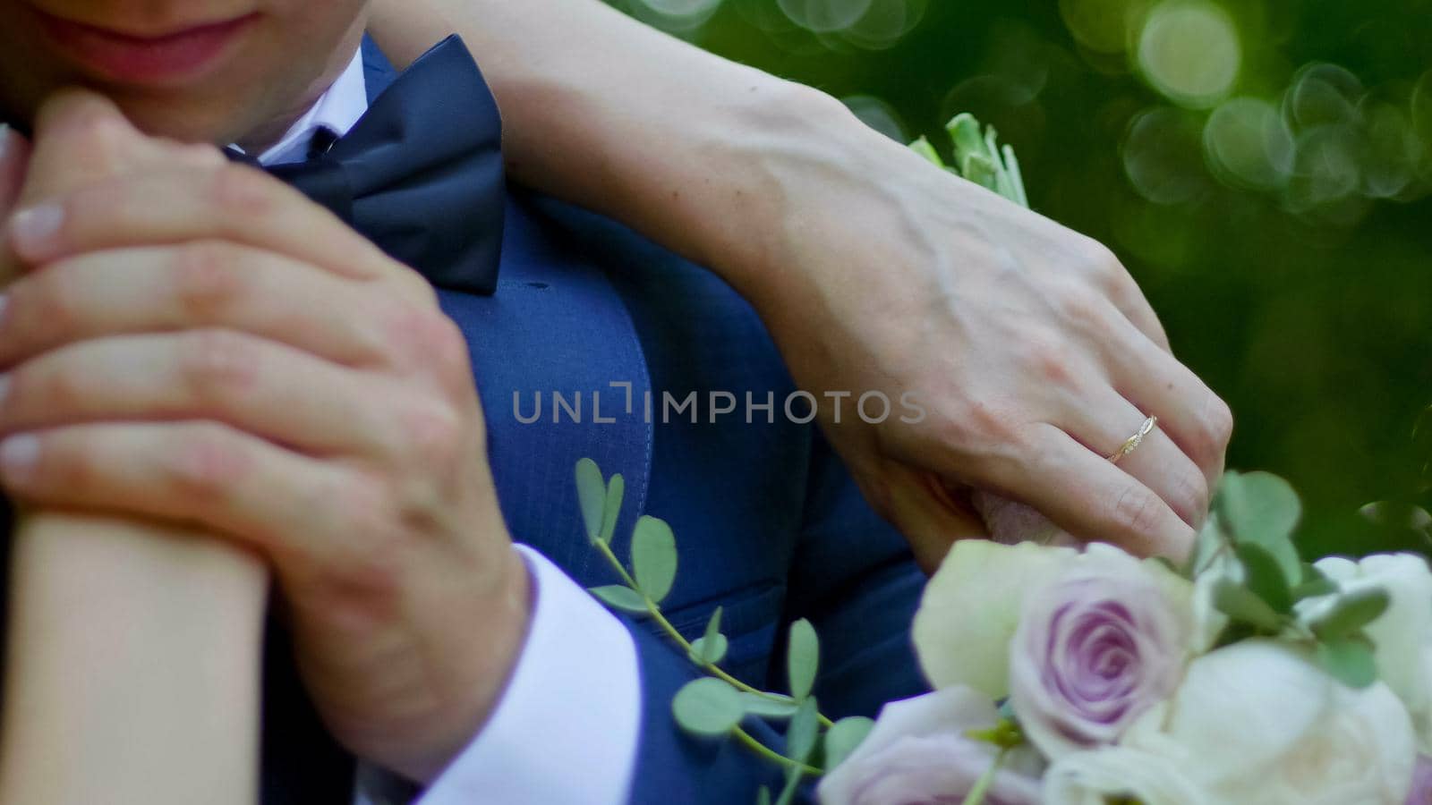 Beautiful bride and groom are kissing in a sunny park, close up, rack focus