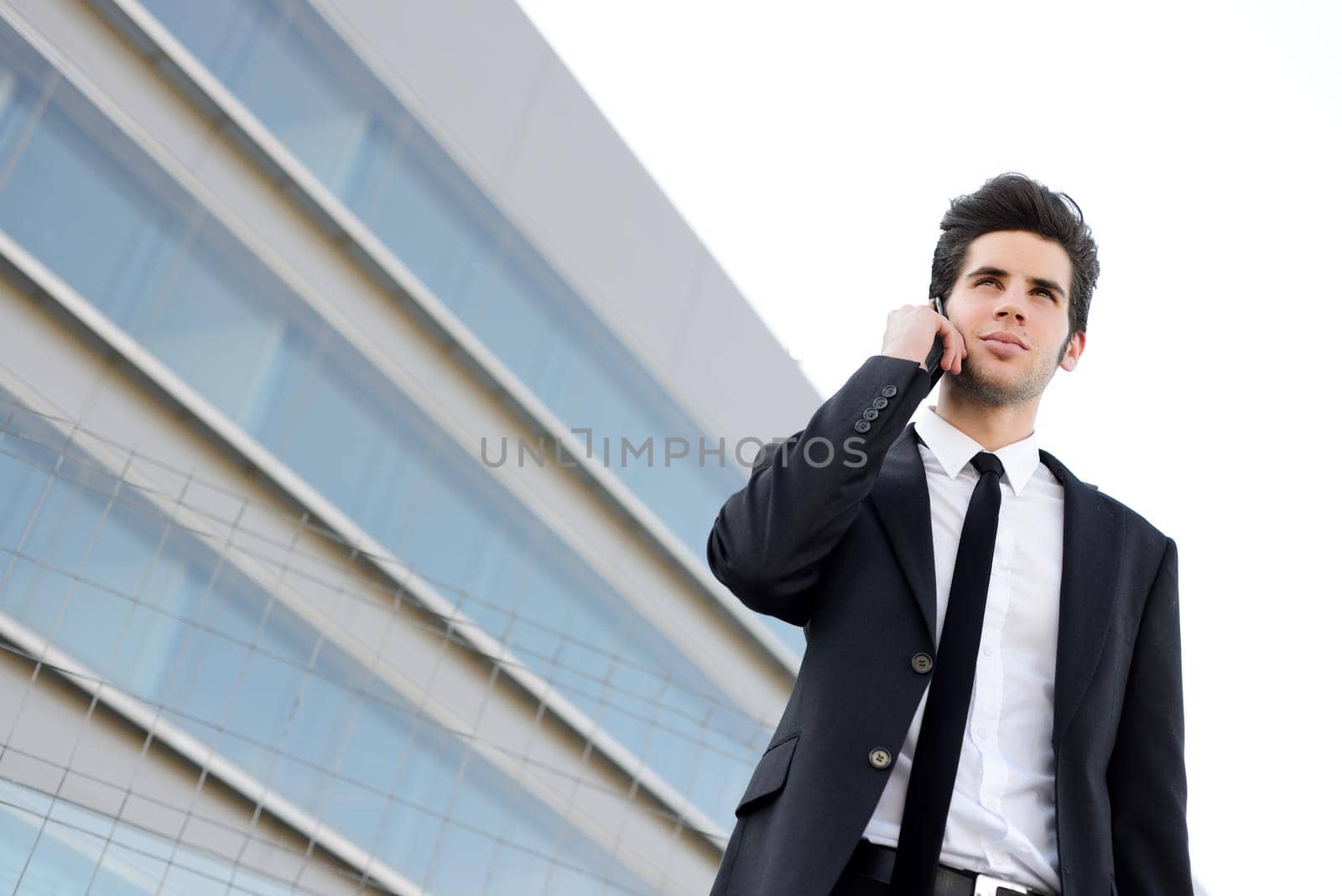 Attractive young businessman on the phone in an office building by javiindy