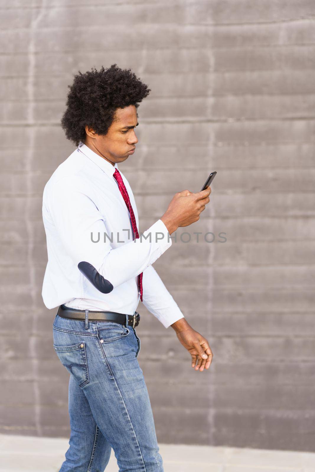 Concerned Black Businessman using his smartphone walking down the street.