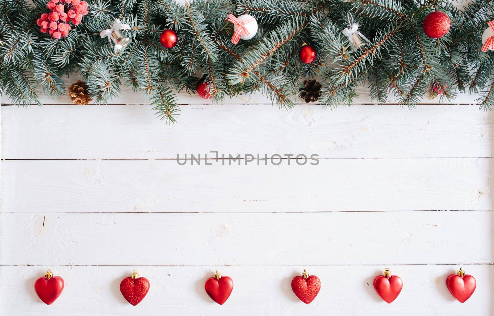 Christmas fir tree on wooden background. Blurred Christmas background, with fir branches, fairy lights and christmas decorations on white wooden plank .