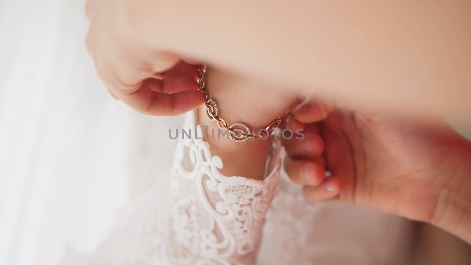 Bridesmaid puts bracelet on the bride's arm , close up