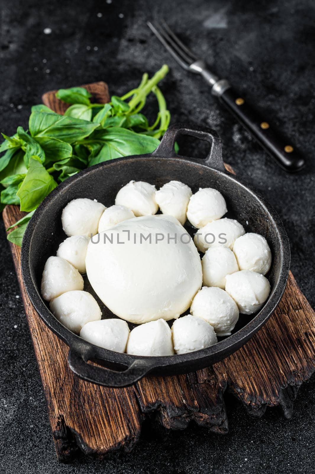 Mozzarella cheese mini balls in pan with basil. Black background. Top view by Composter