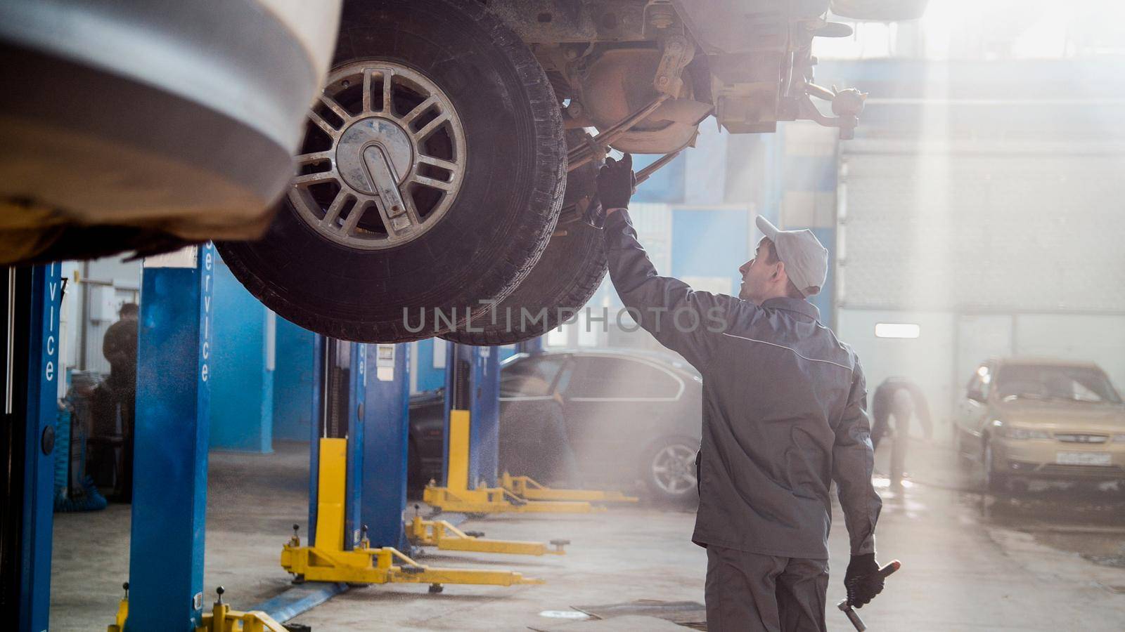 Garage automobile service - a mechanic checks the transmission, wide angle