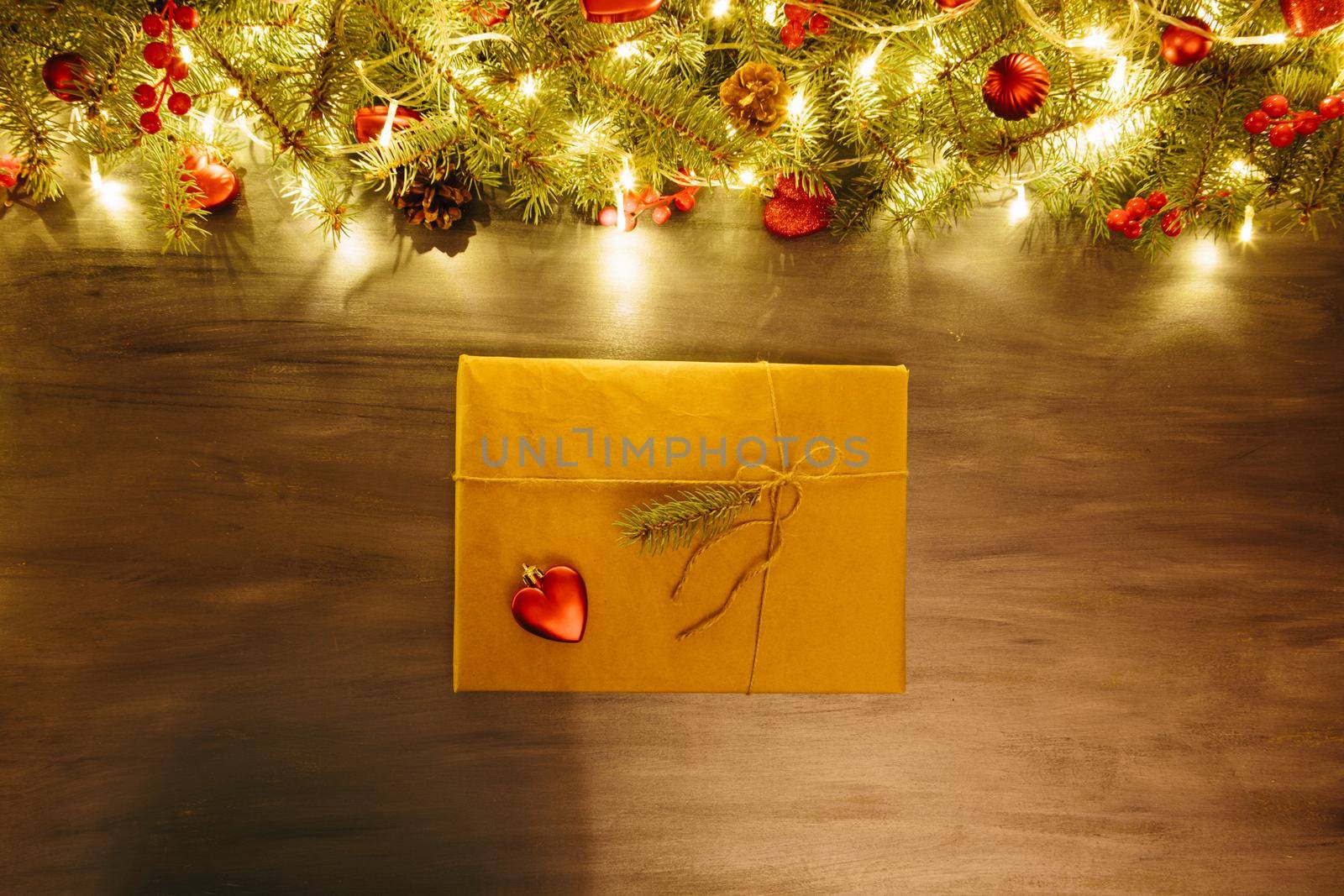 Gray wooden christmas background with gift box, fir-tree branch and red christmas decorations in the corner. Frame. View from above .