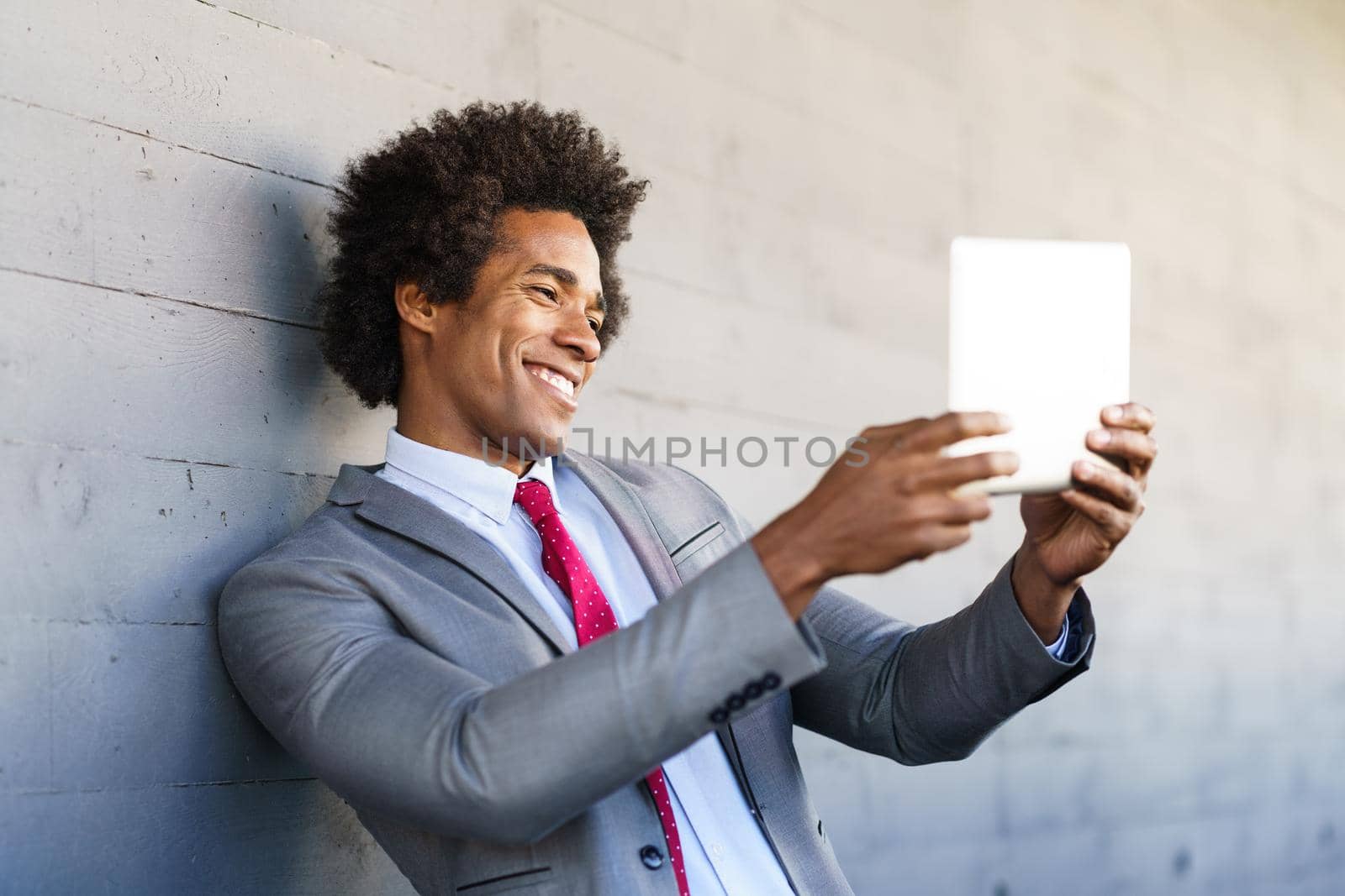 Black Businessman using a digital tablet in urban background. Man with afro hair.