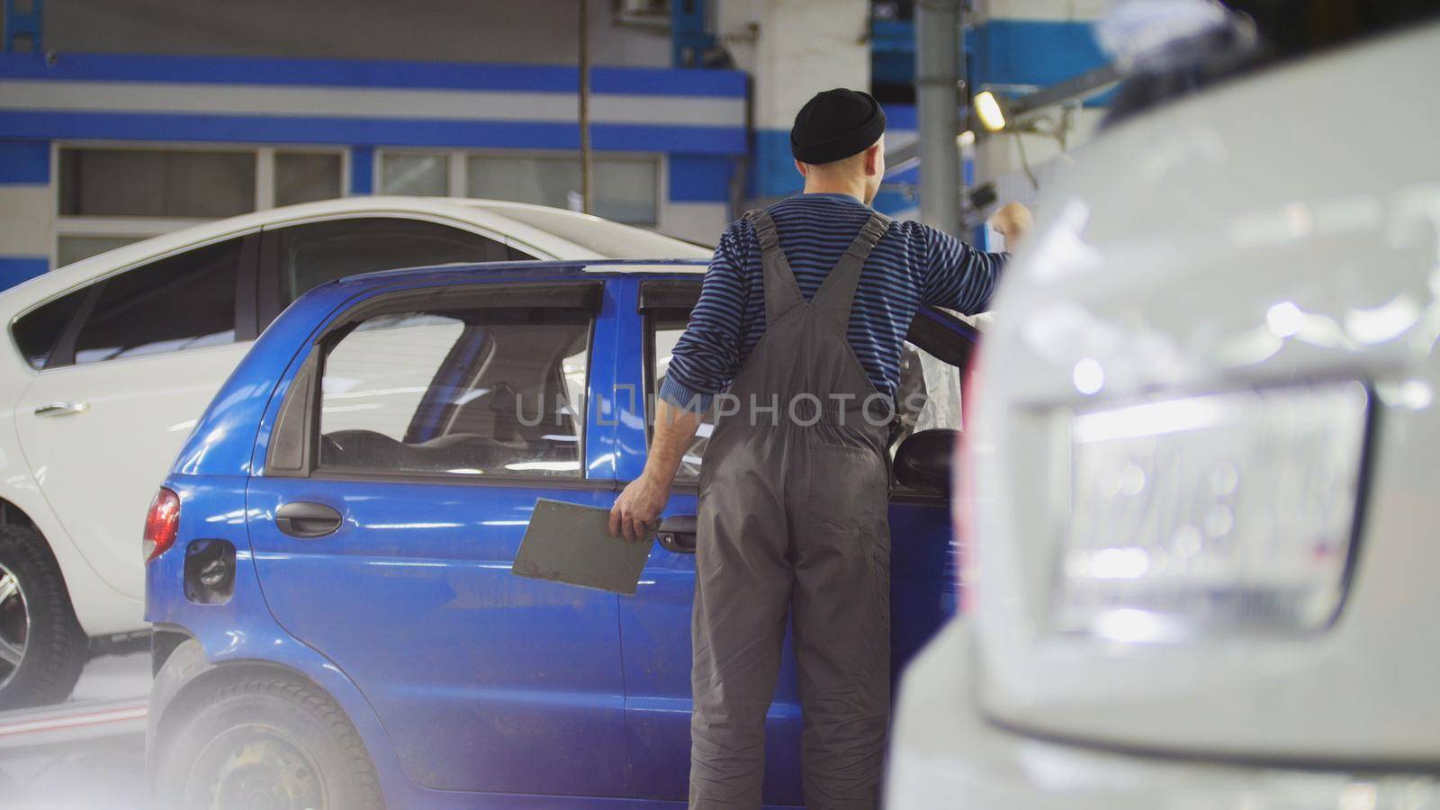 Worker in auto service preparing car for professional diagnostic, close up, wide angle