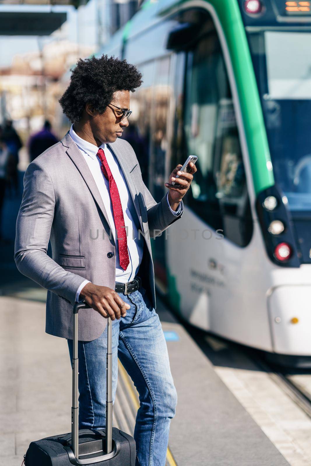 Black Businessman wearing suit waiting his train on an outdoors station. Man with afro hair.