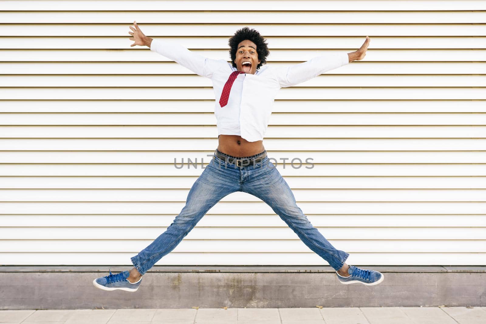 Black Businessman jumping outdoors. Happy Man with afro hair.