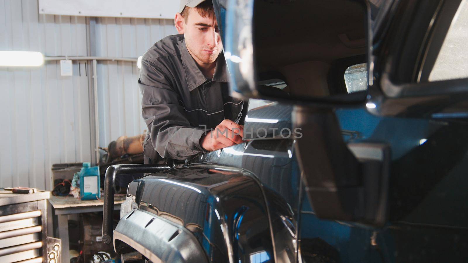 Mechanic looking to hood of the car - automobile service repairing, close up